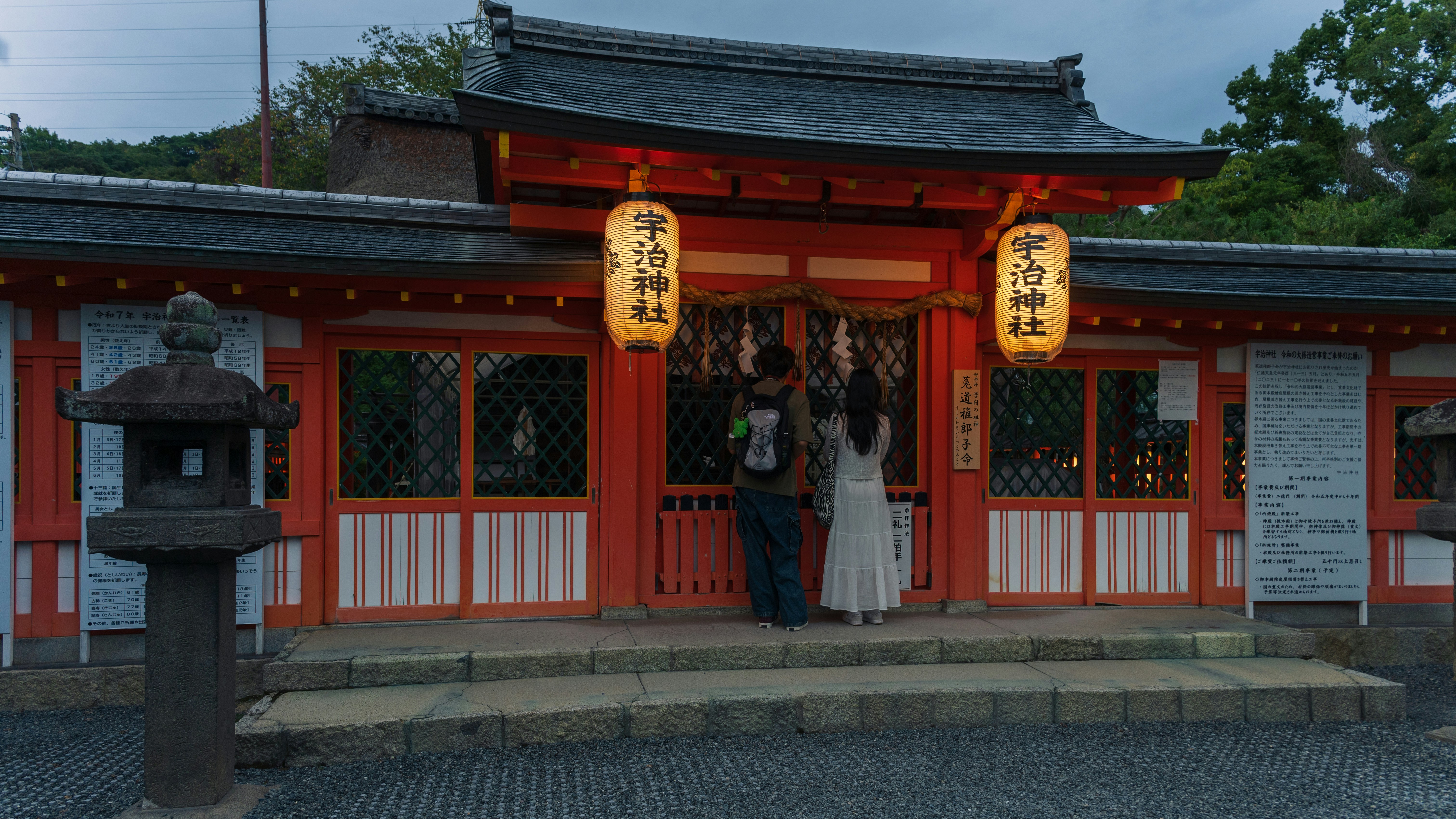 明るく照らされた神社の前に立つ二人