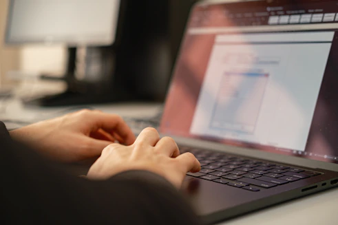 Person typing on a laptop computer keyboard.