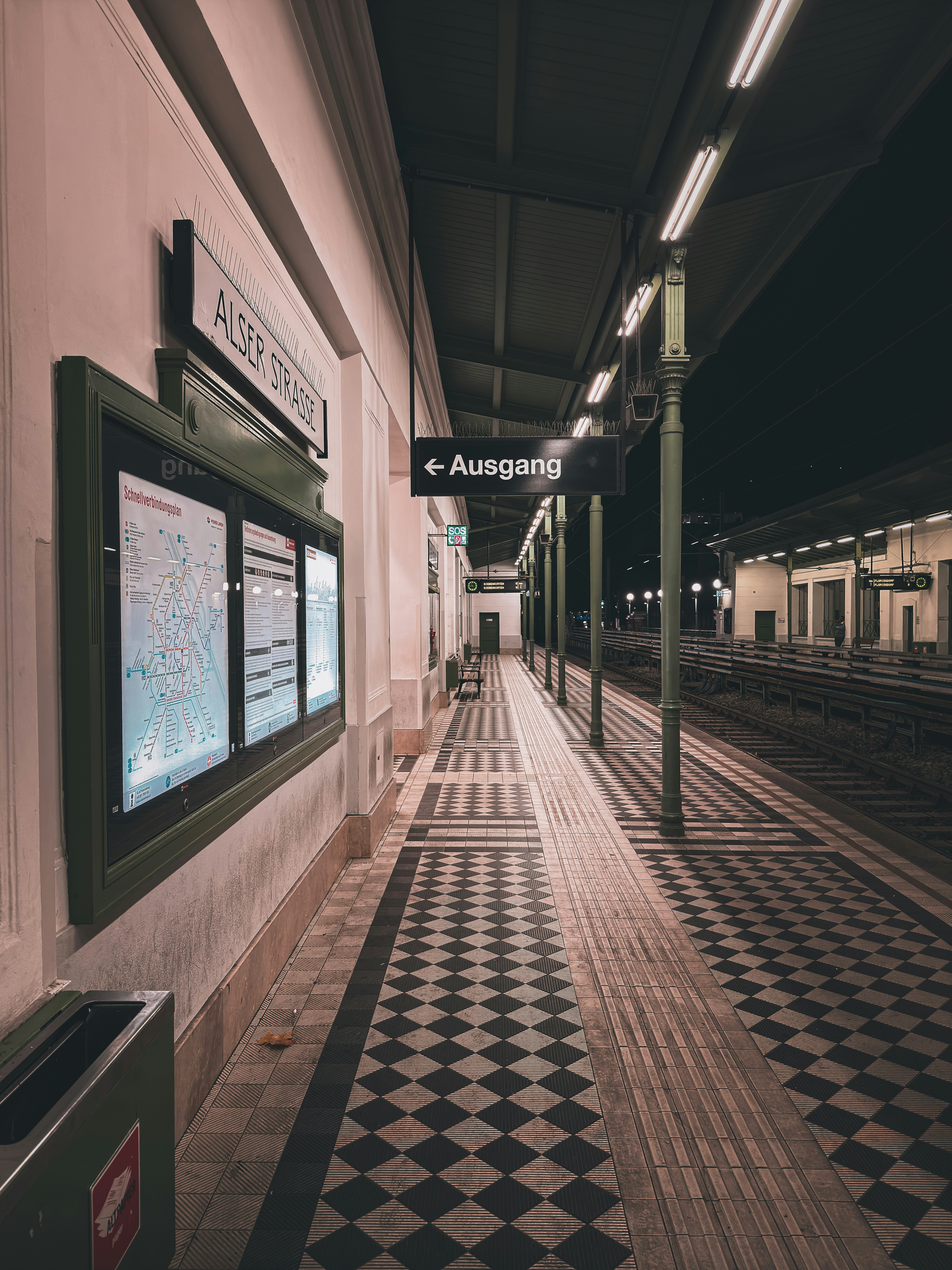 Empty train station platform at night with checkered floor.