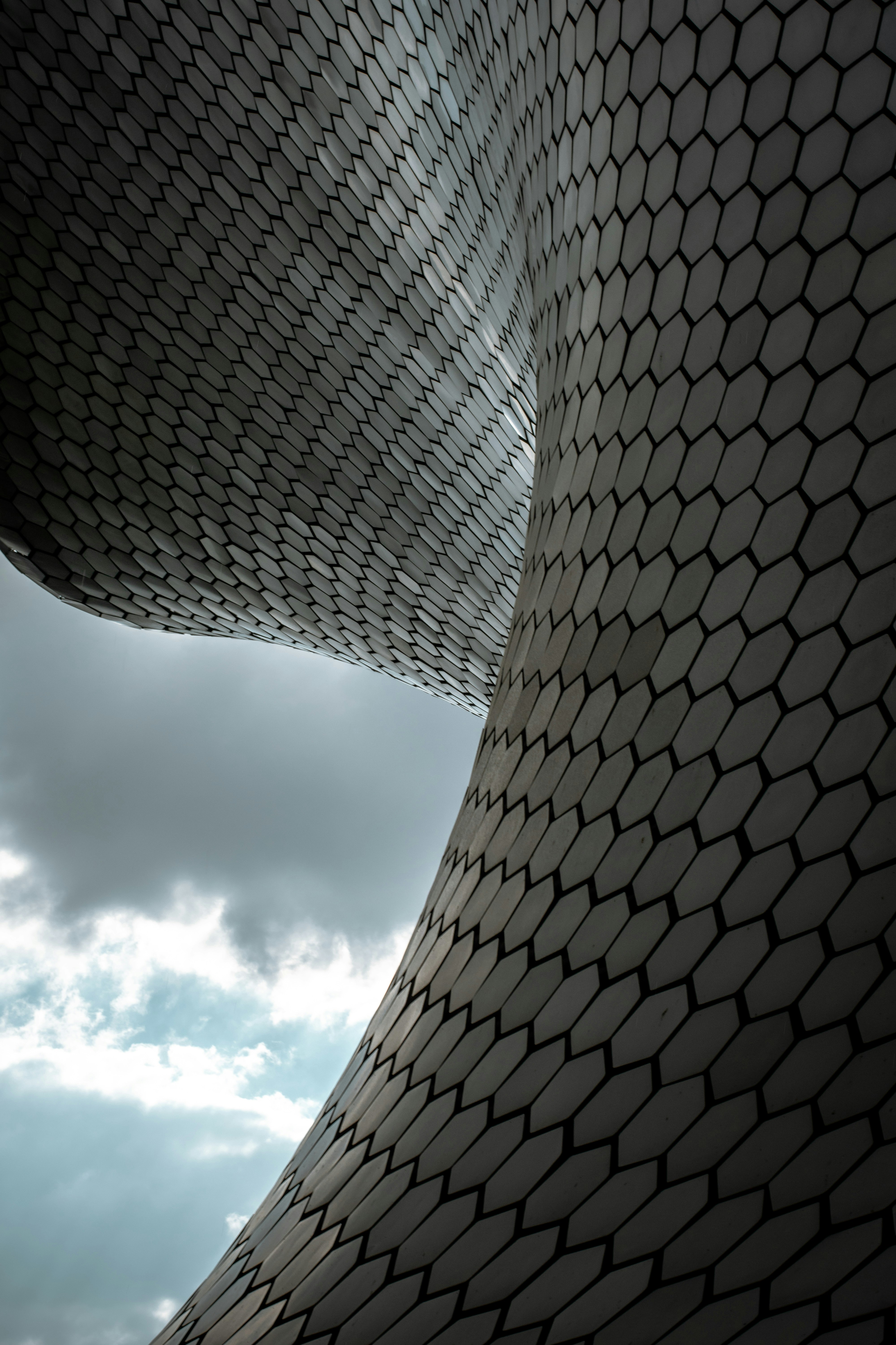 Modern building with hexagonal facade against cloudy sky