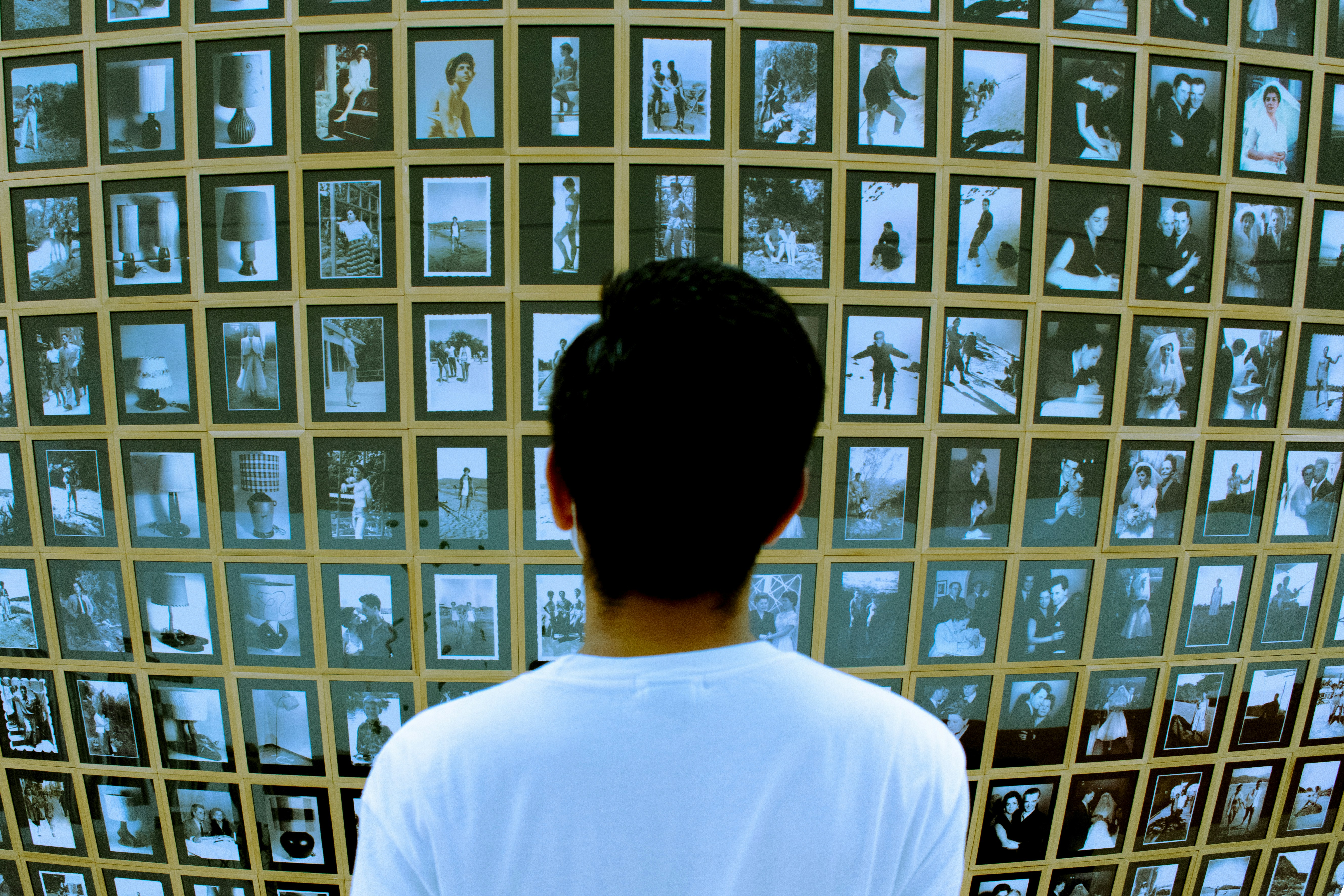 Man looks at wall of framed vintage photographs