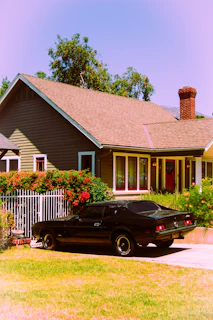 Black vintage car parked in front of a suburban house