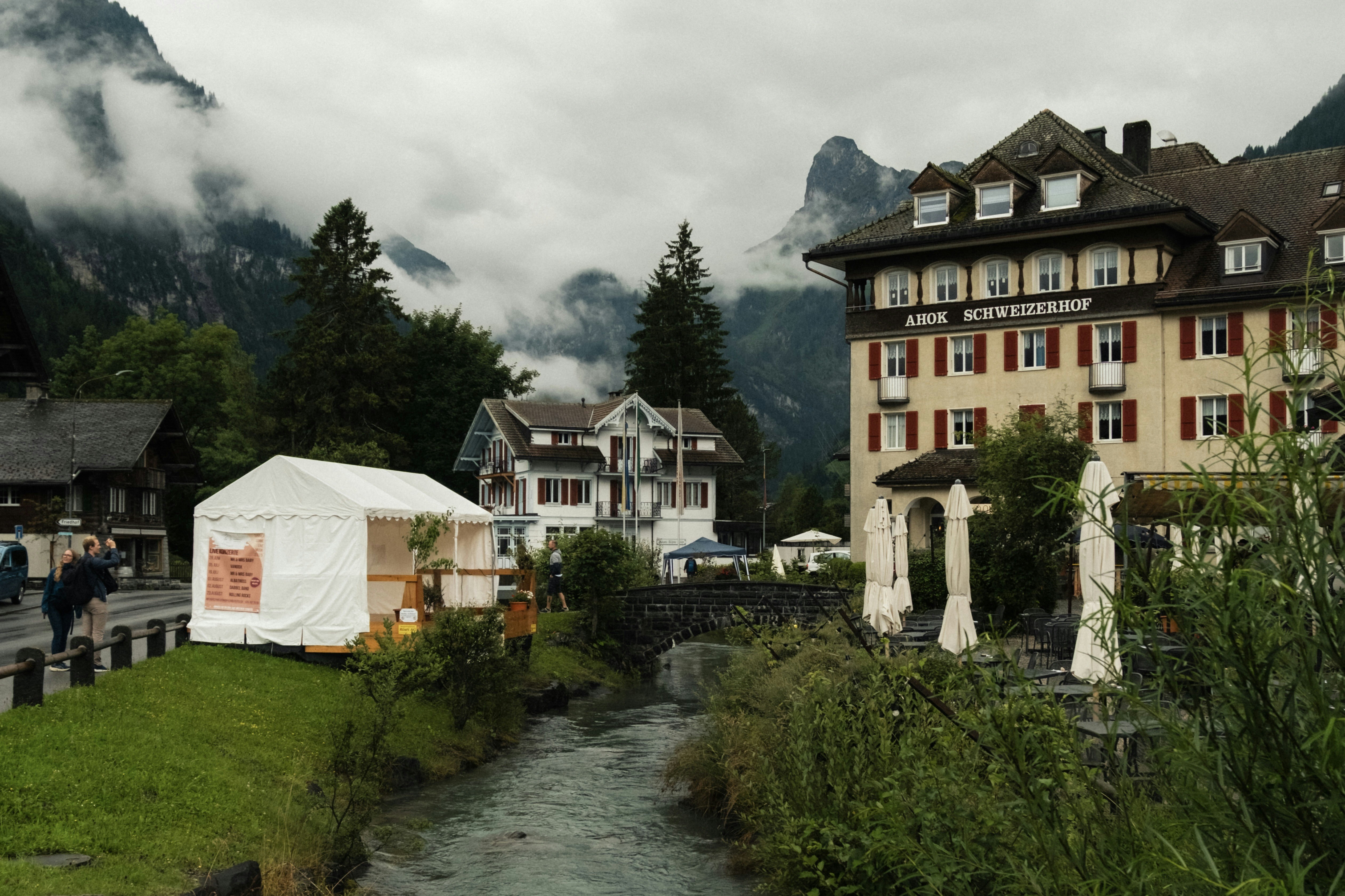 Buildings and a river in a foggy mountain village.