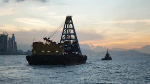 Crane barge and tugboat on the water at sunset