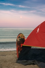 Tent and surfboard on beach with moonlit sky
