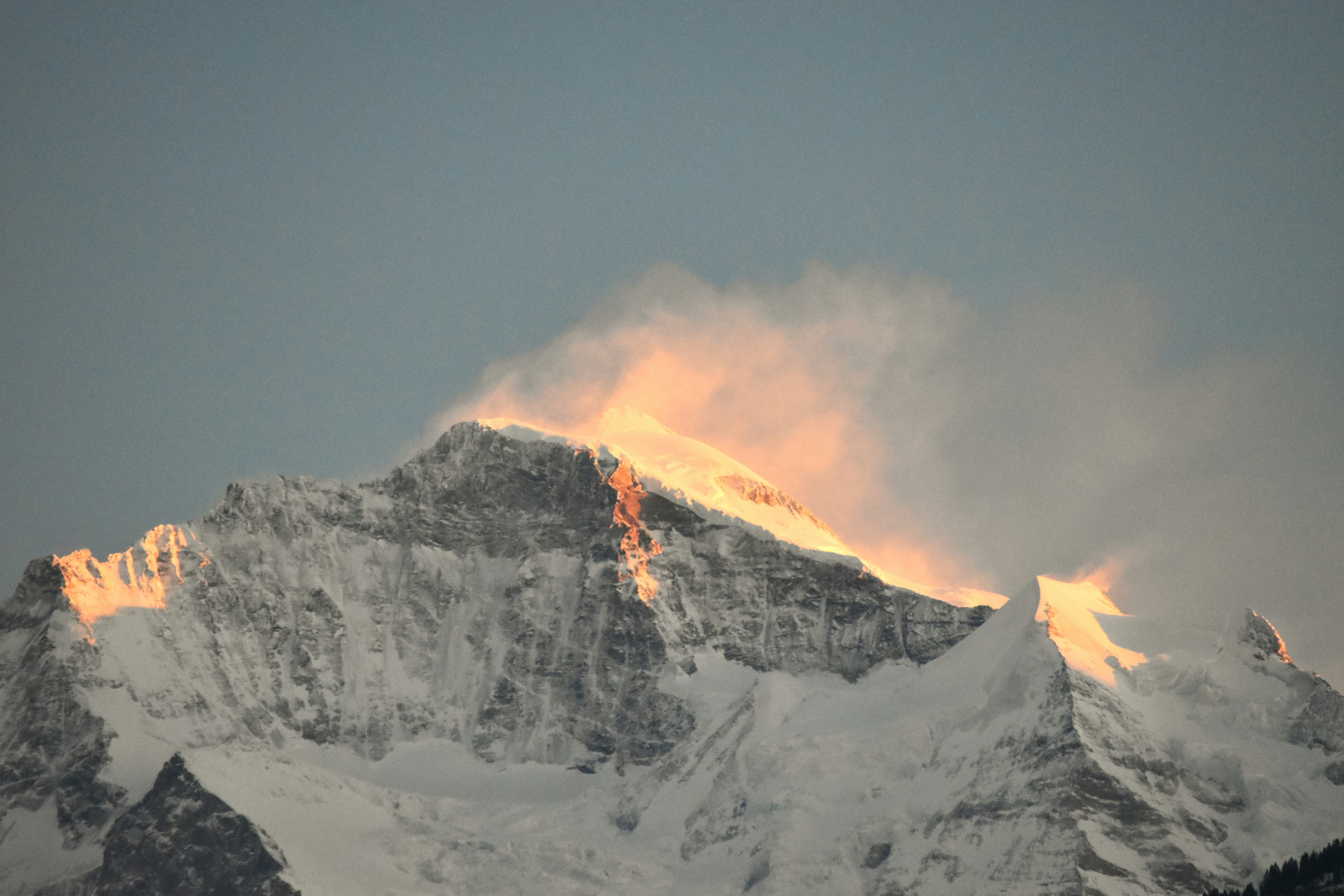 Snowy mountain peak illuminated by golden sunset light