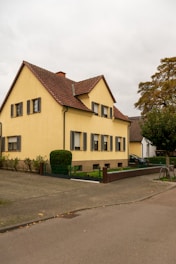 A yellow two-story house with a brown roof.