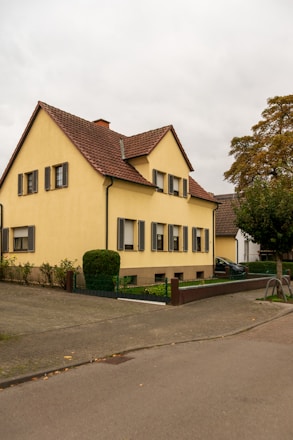 A yellow two-story house with a brown roof.
