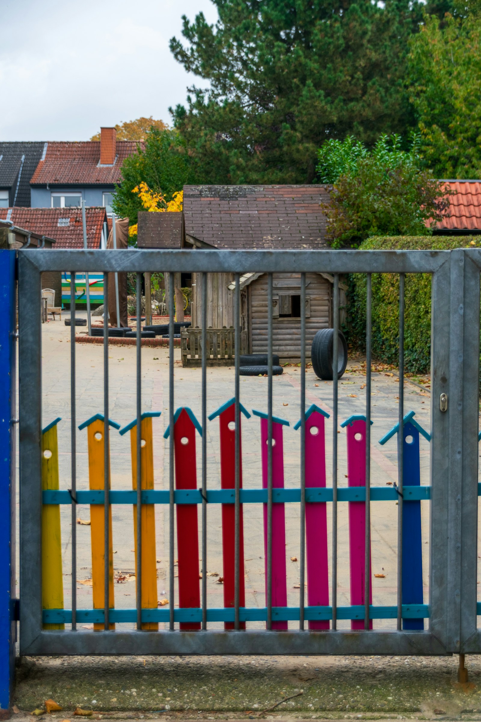 A colorful locked gate at the entrance of the playground, part of the secure perimeter