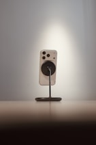 Smartphone on a stand against a spotlighted wall.