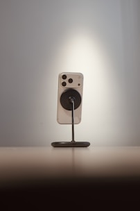 Smartphone on a stand against a spotlighted wall.