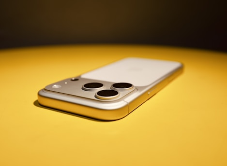 Smartphone with three cameras on yellow surface