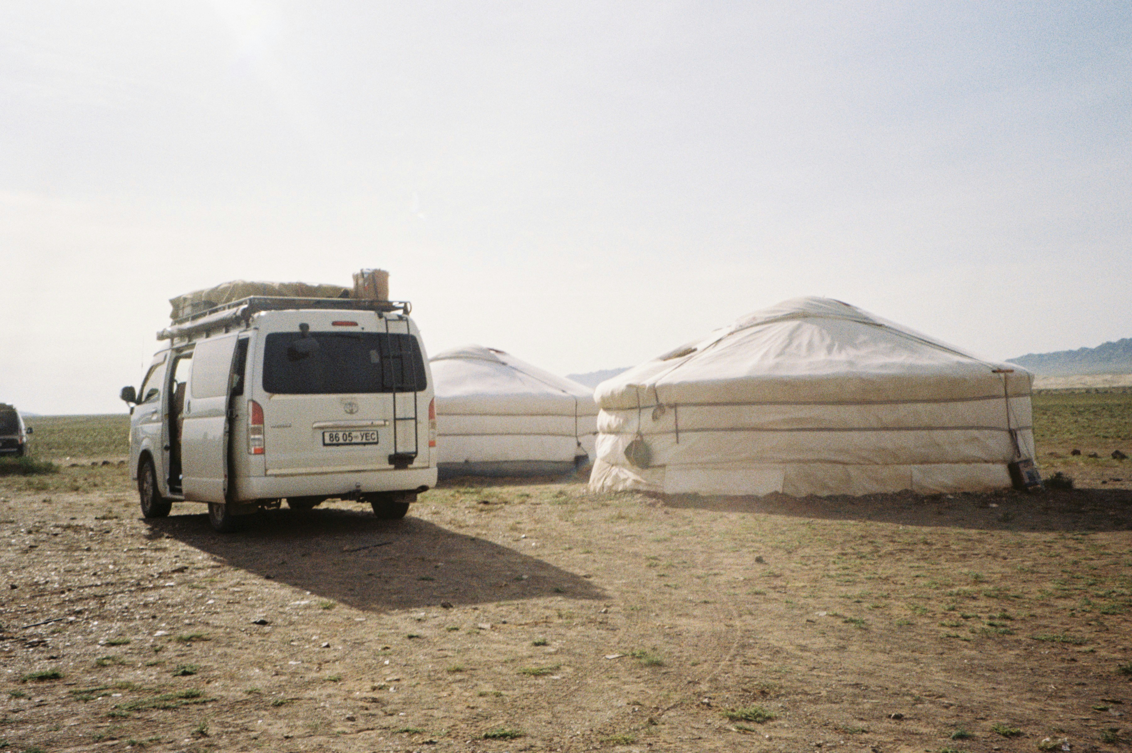 White van parked near yurts on a sunny day