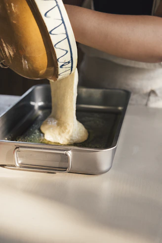 Dough being poured into a baking pan.