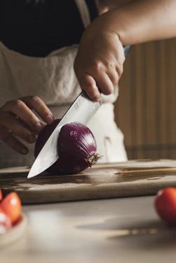 Person slicing a red onion on a cutting board