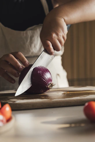 Person slicing a red onion on a cutting board.