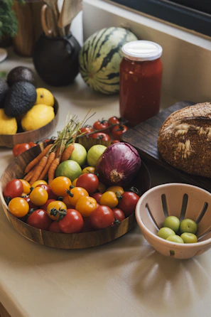 Fresh produce including tomatoes, carrots, and avocados on a counter.