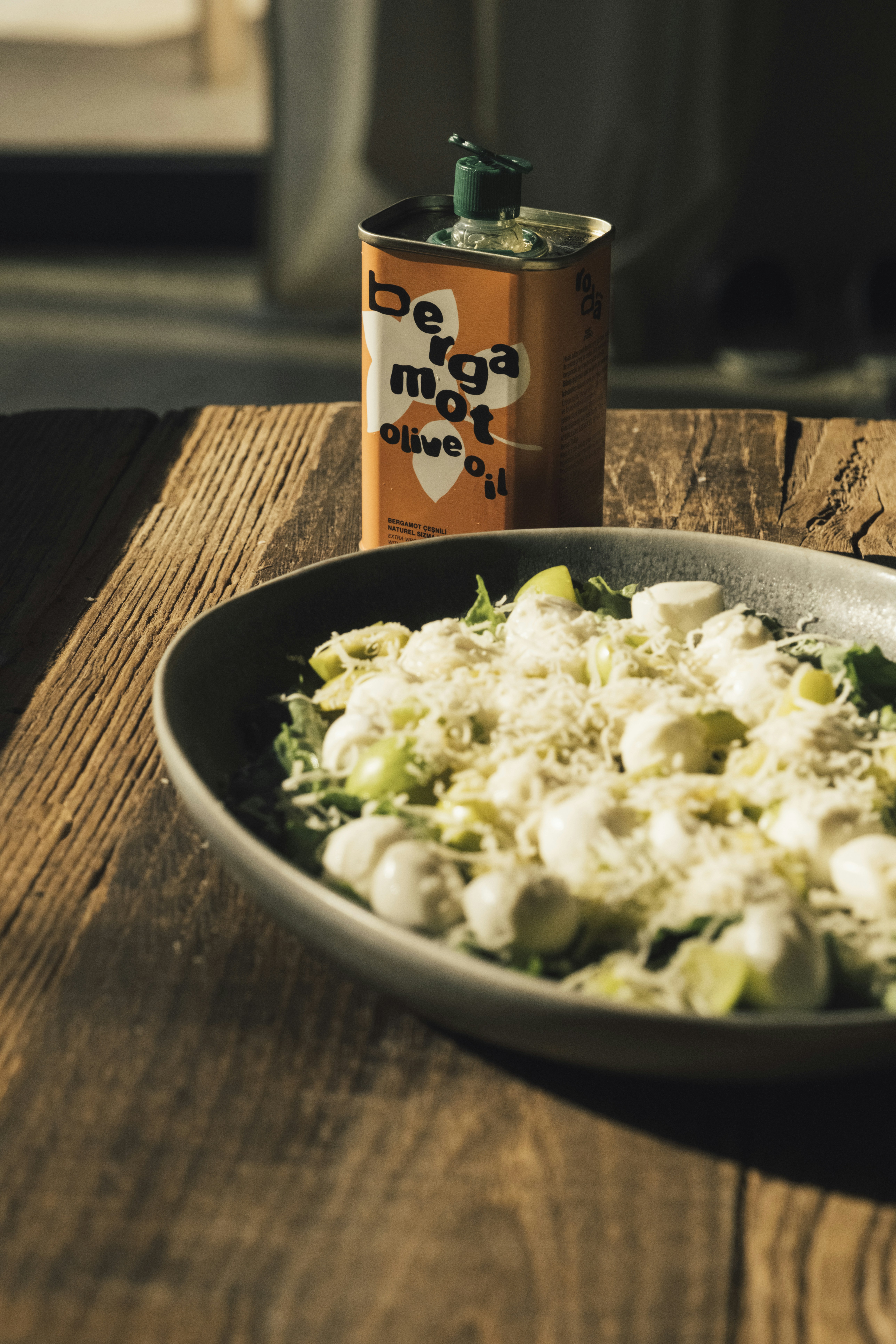 Salad with mozzarella and grapes next to olive oil can.