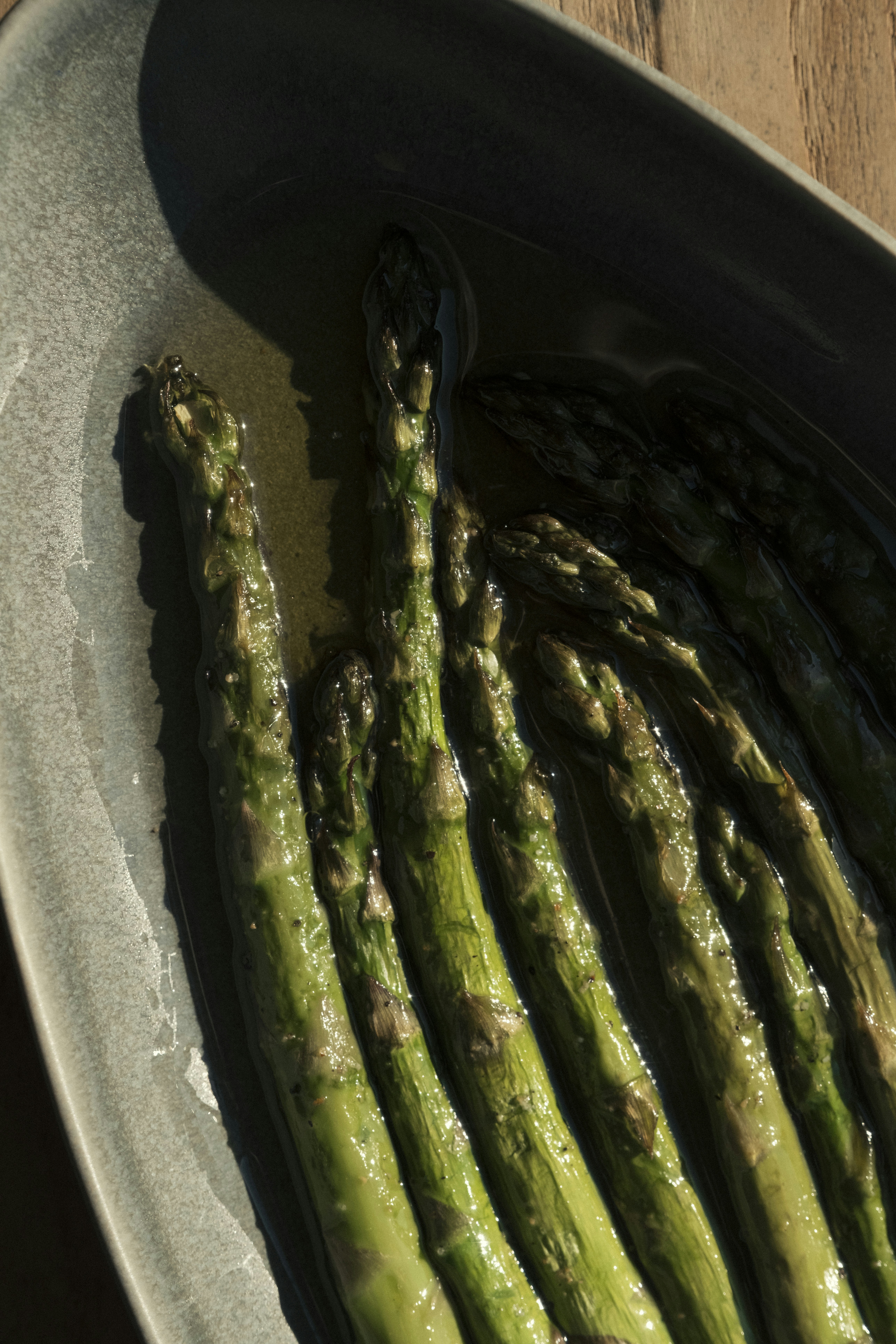 Cooked asparagus spears in a grey dish.