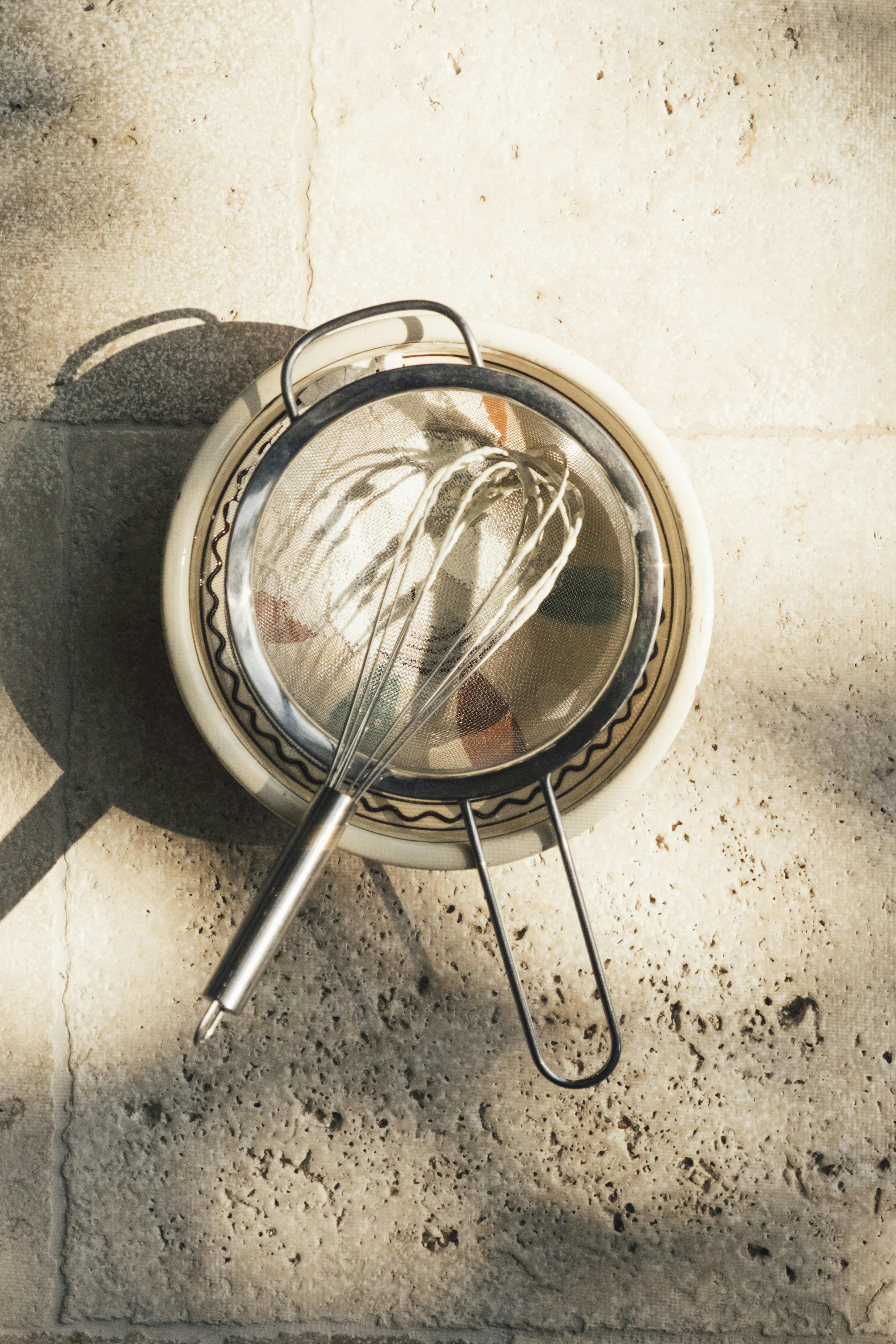 Whisk and sieve on a textured surface