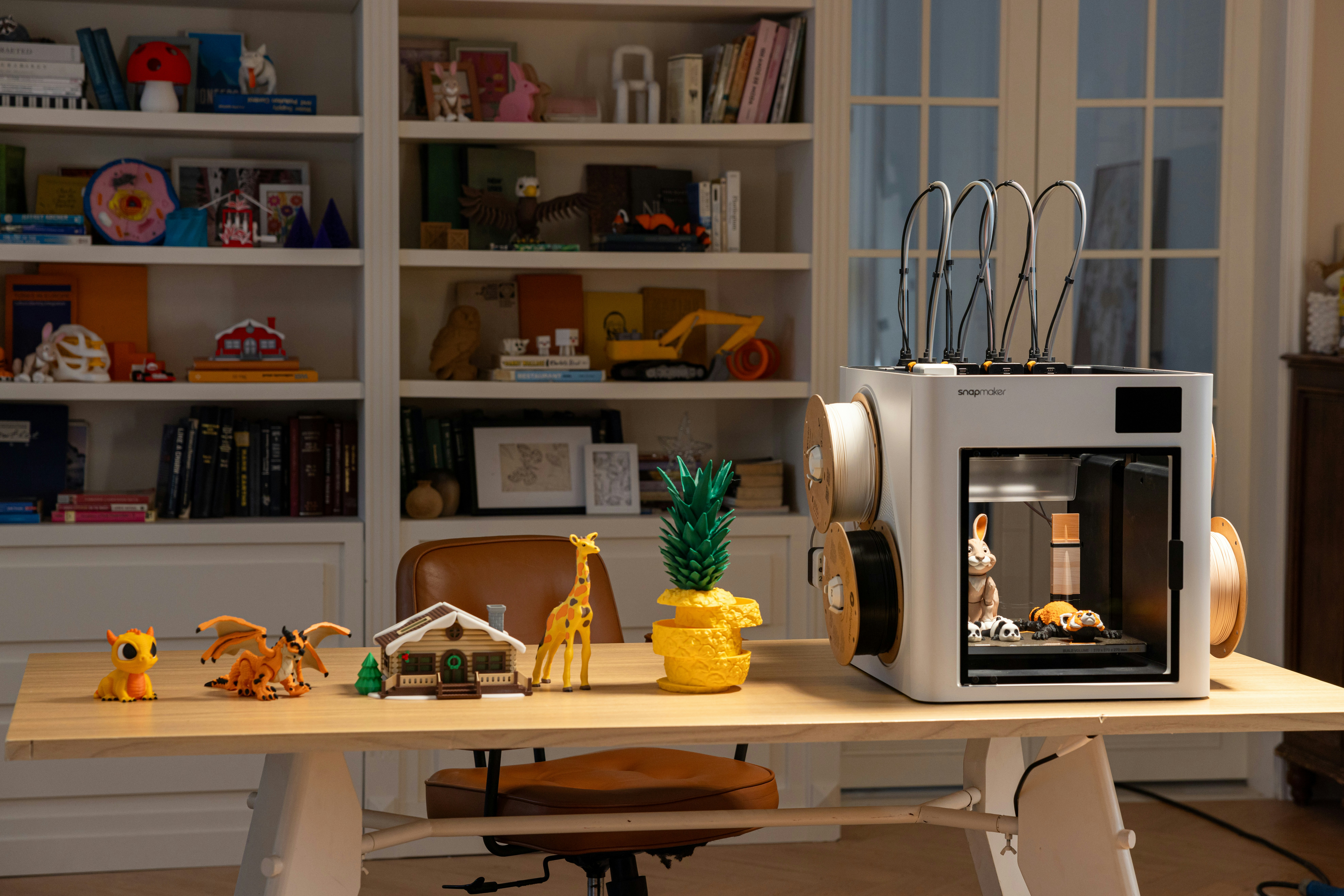 A desk displays vibrant models as the Snapmaker U1 color 3D printer continues producing detailed multi material parts with accuracy
