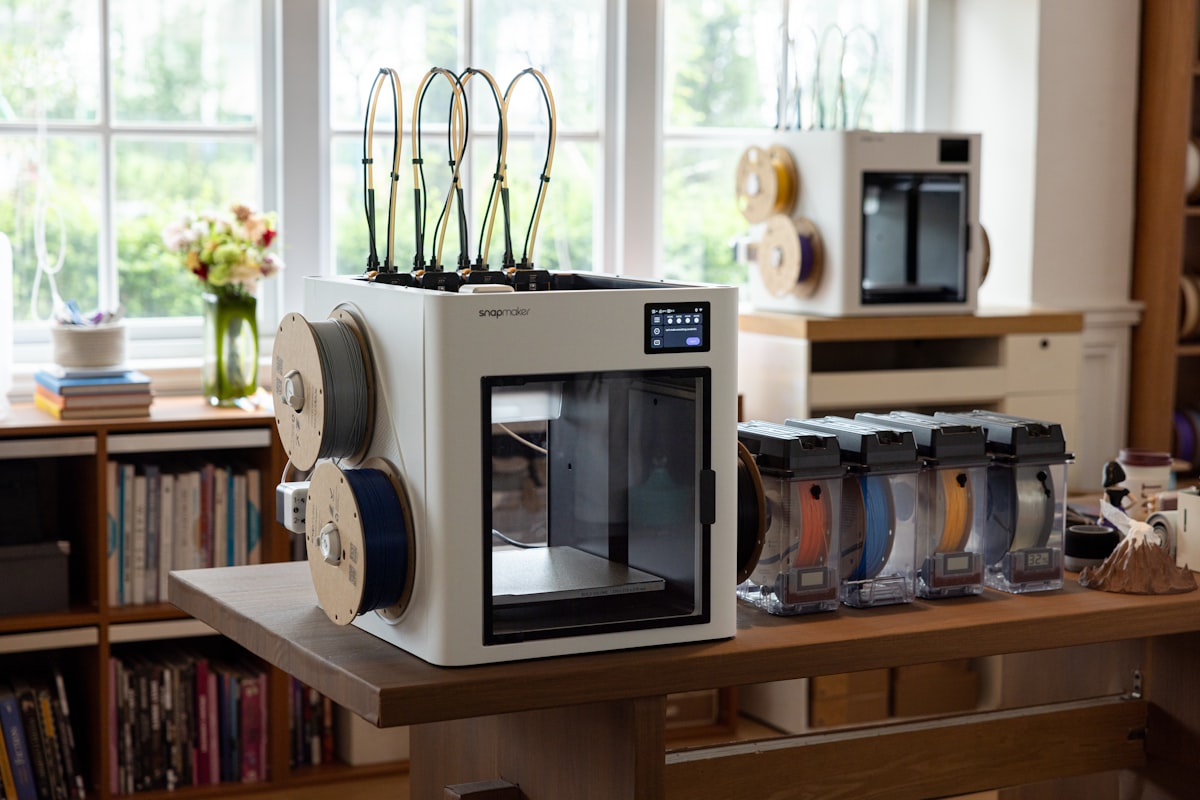 3D printer setup with multiple filament spools on table — home 3D printing workspace with multi-color printing capability