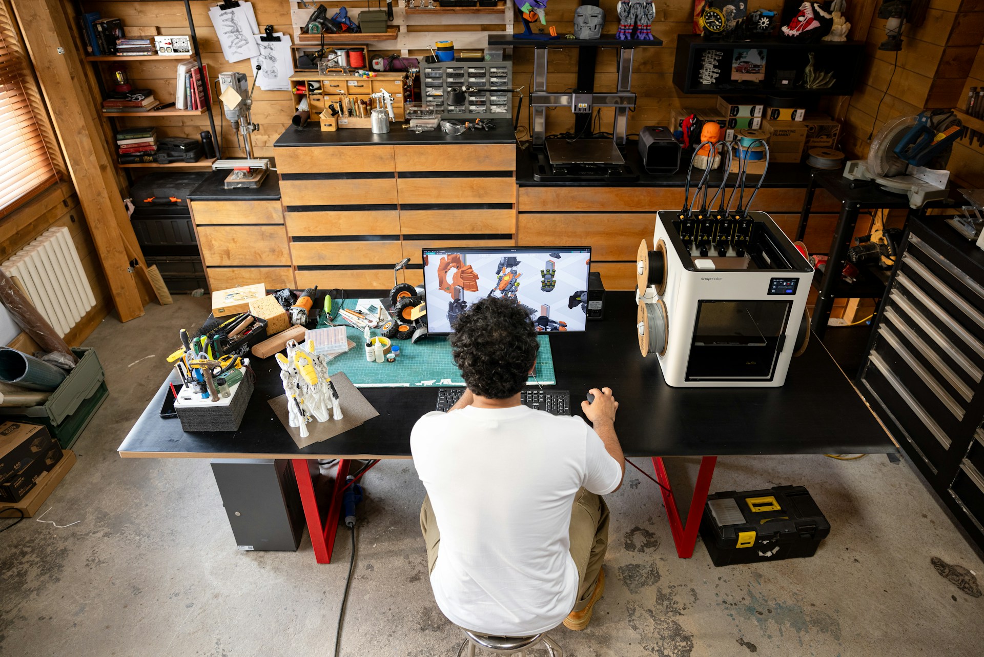 Man working at a desk with 3D printer.