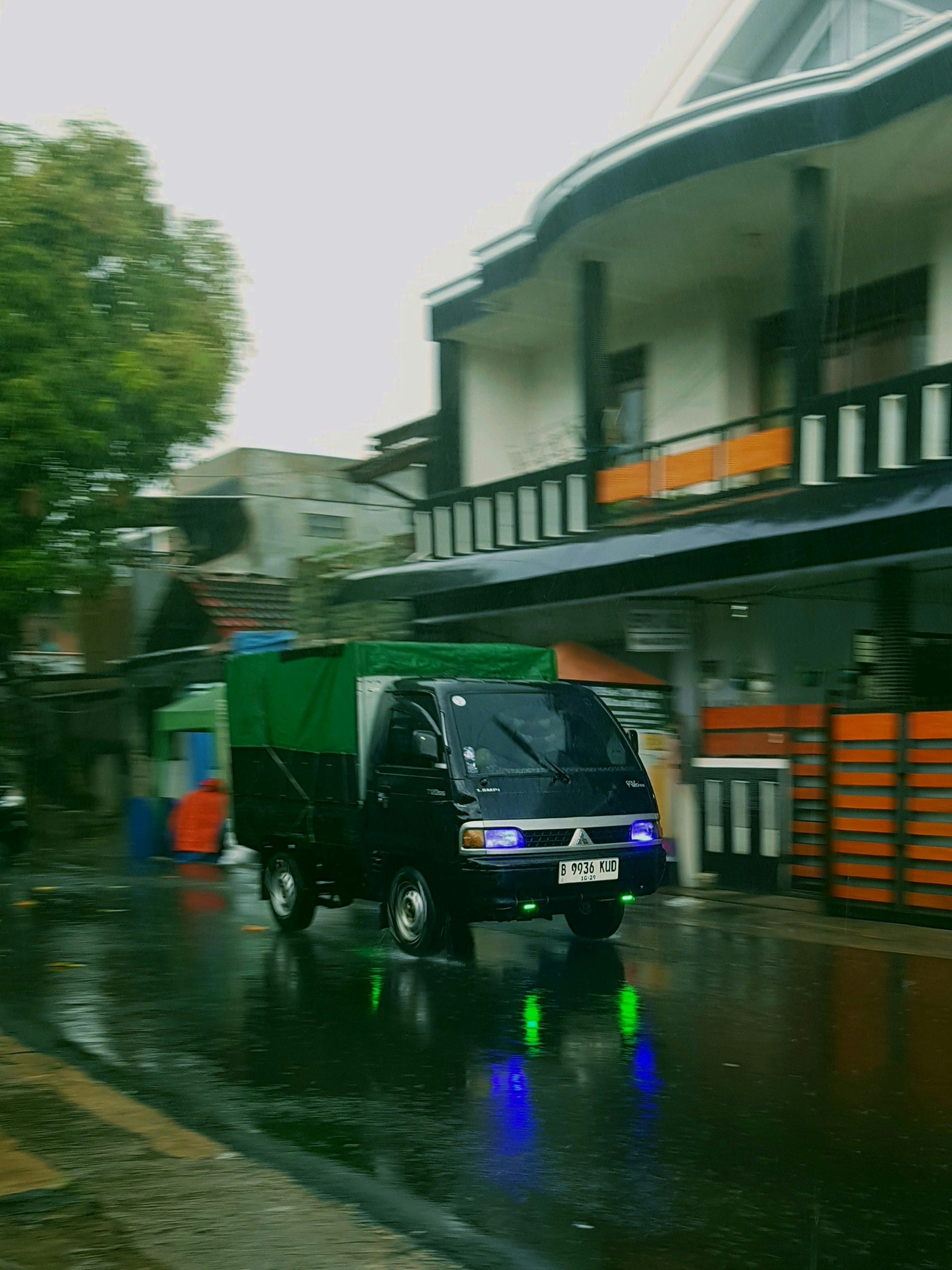 A black truck drives down a wet street