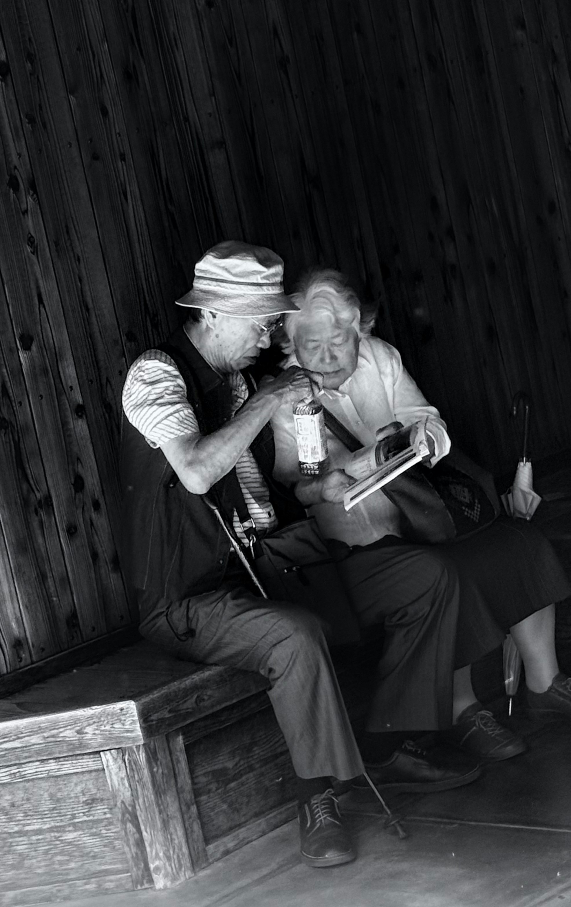 Elderly couple sharing a drink and a book.
