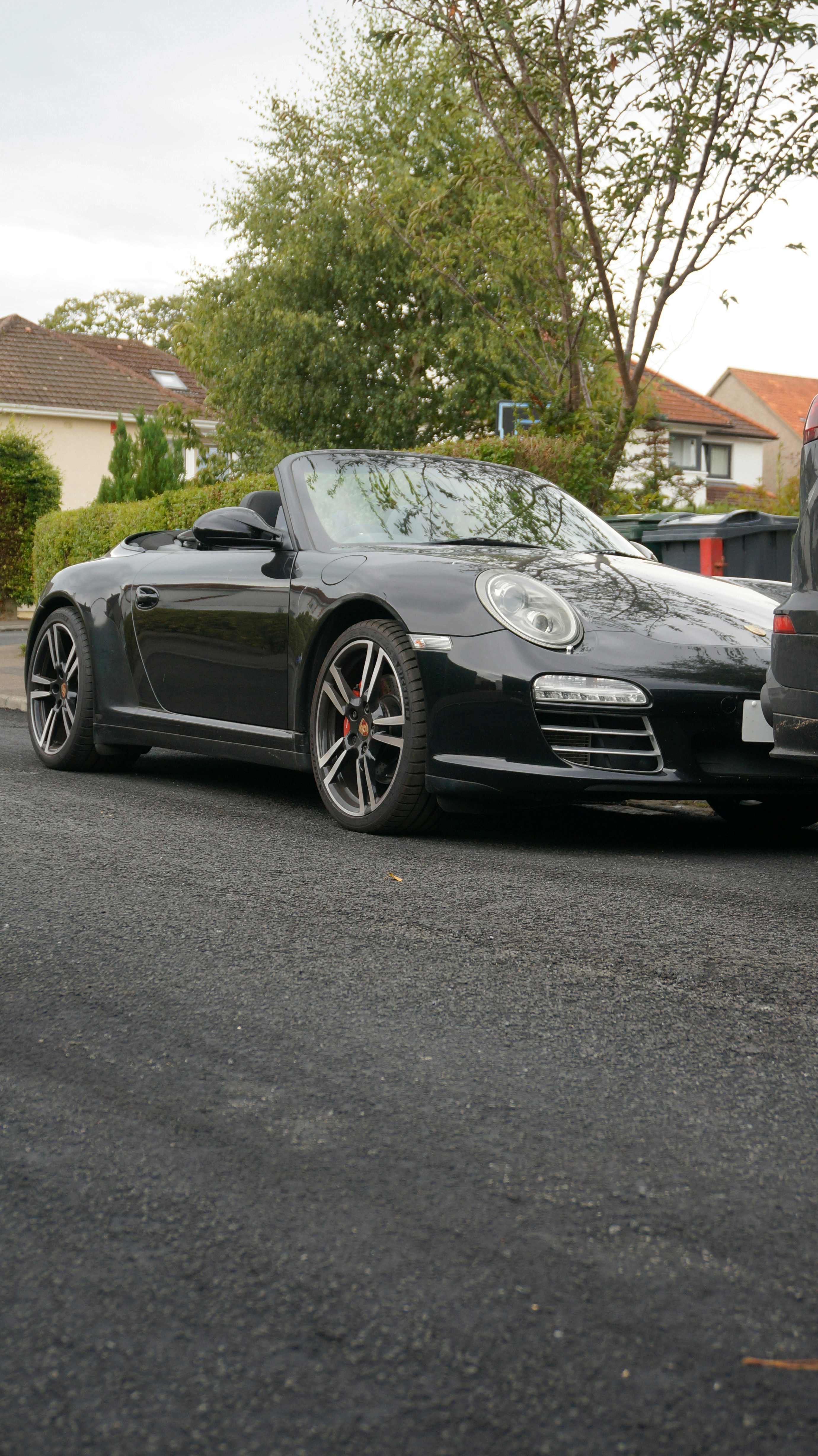 Black convertible sports car parked on asphalt road.