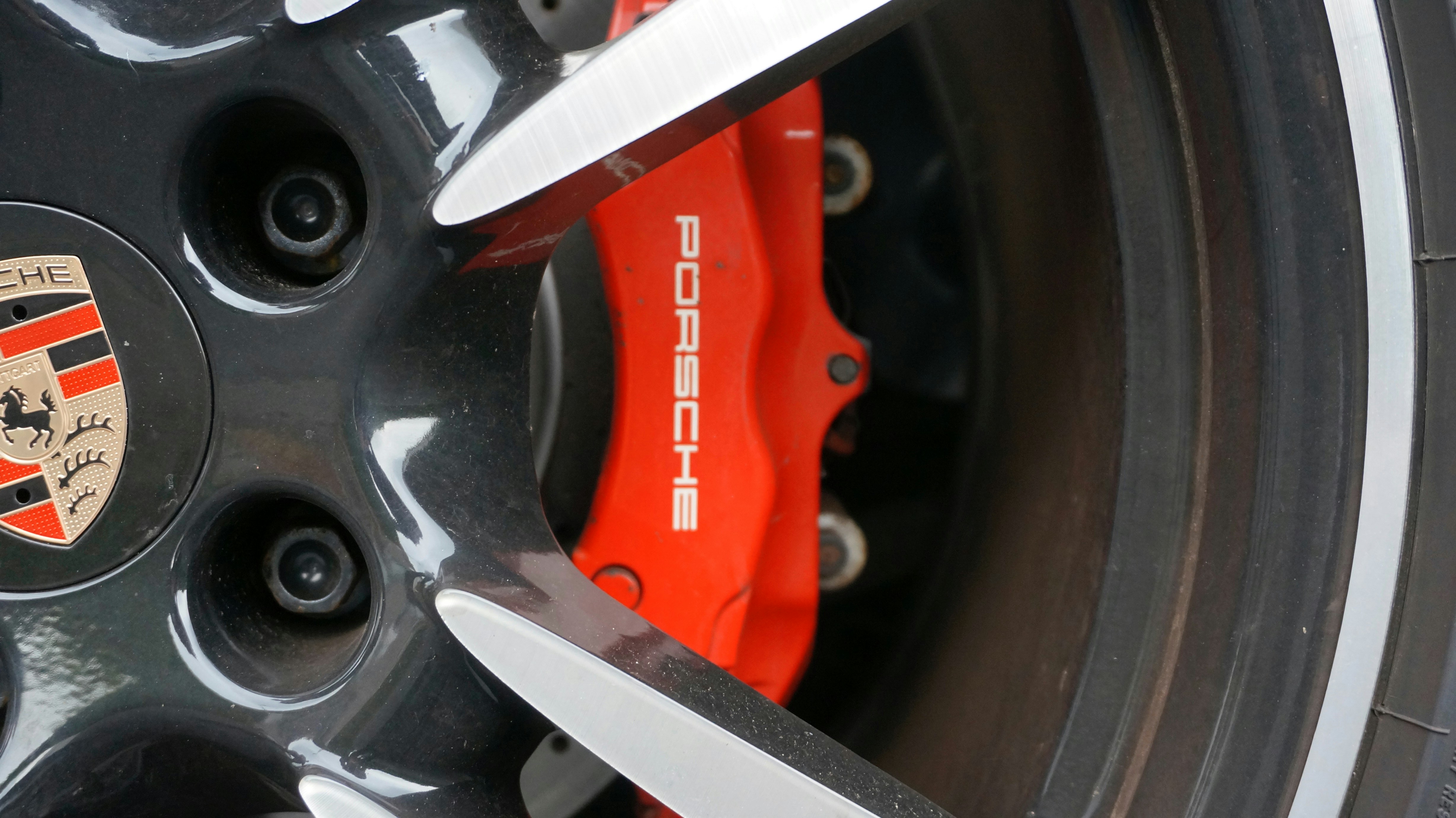 Closeup of an electric vehicle wheel and brake rotor, showing the traditional friction braking hardware used alongside regenerative braking.