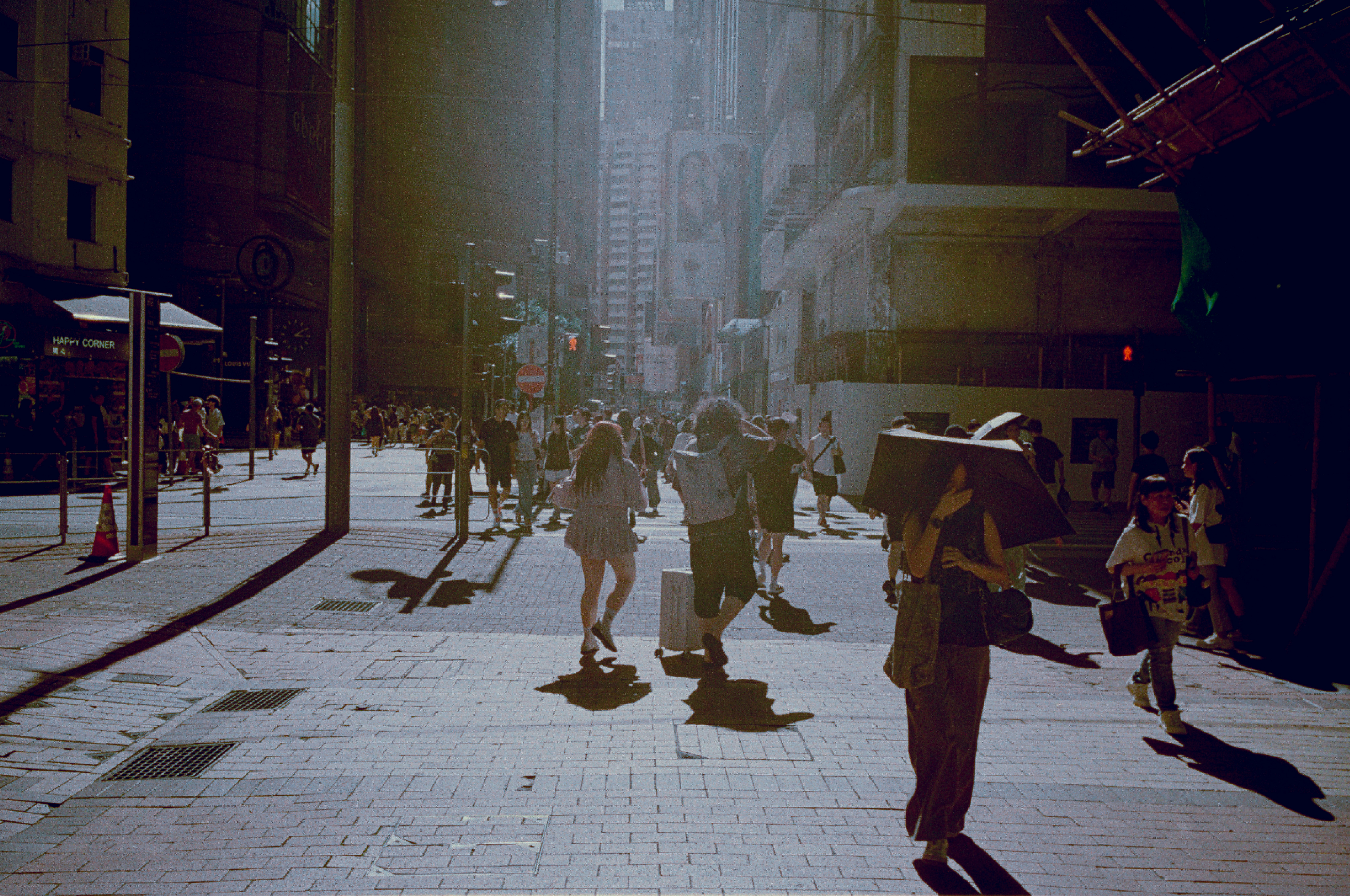 People walking down a sunlit city street.