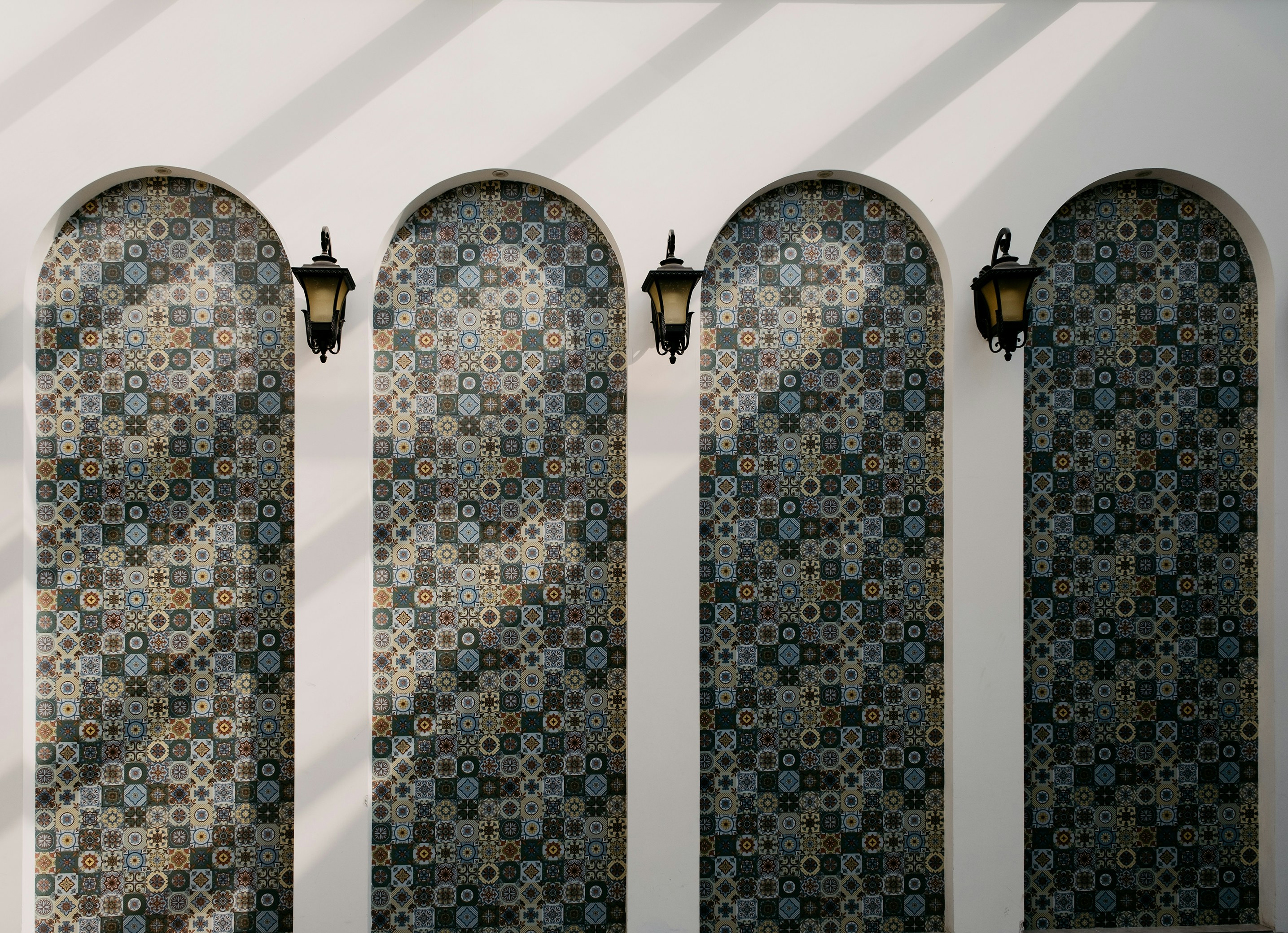 Four arched alcoves with patterned tiles and lamps