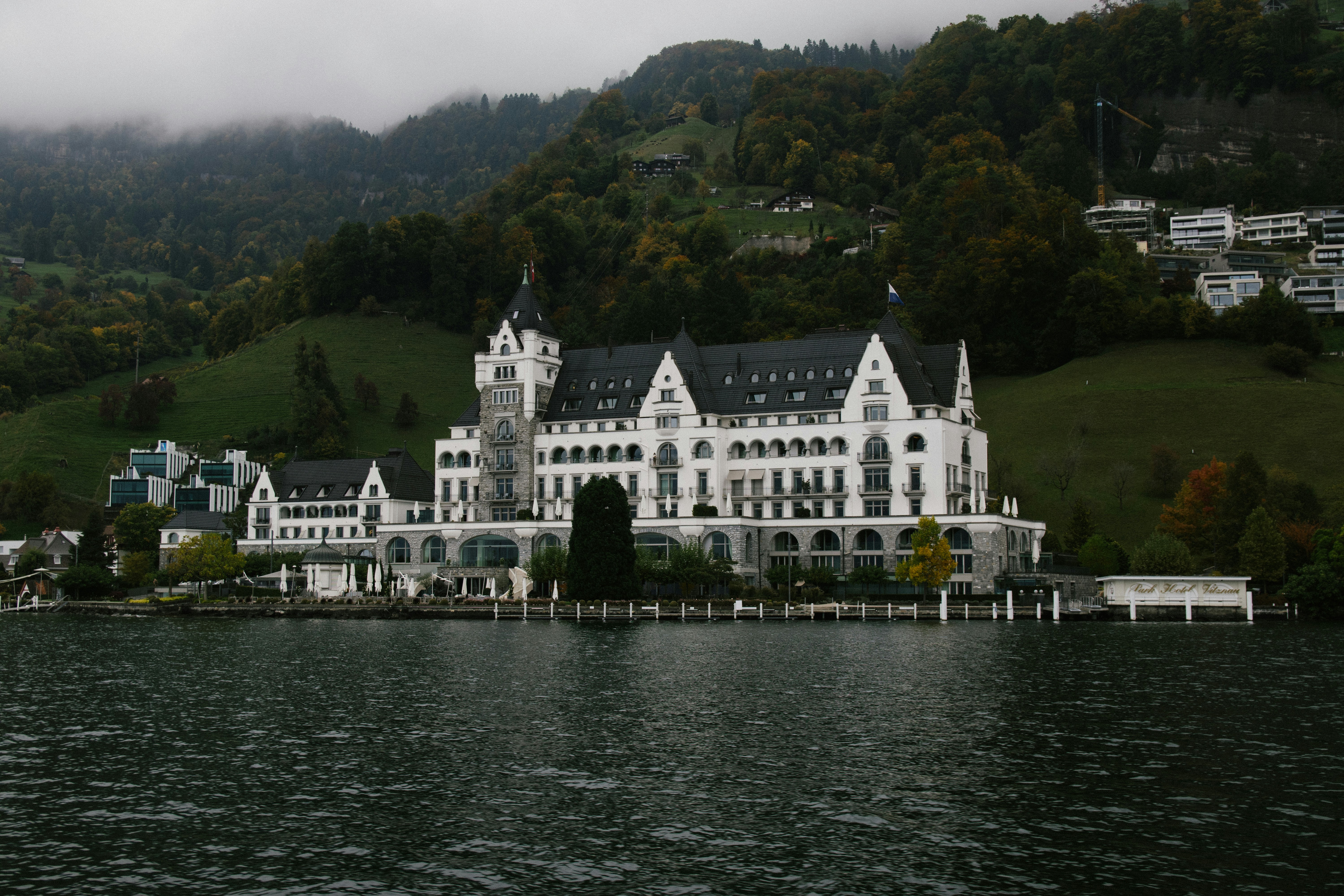 Grand white building on a lake with hills