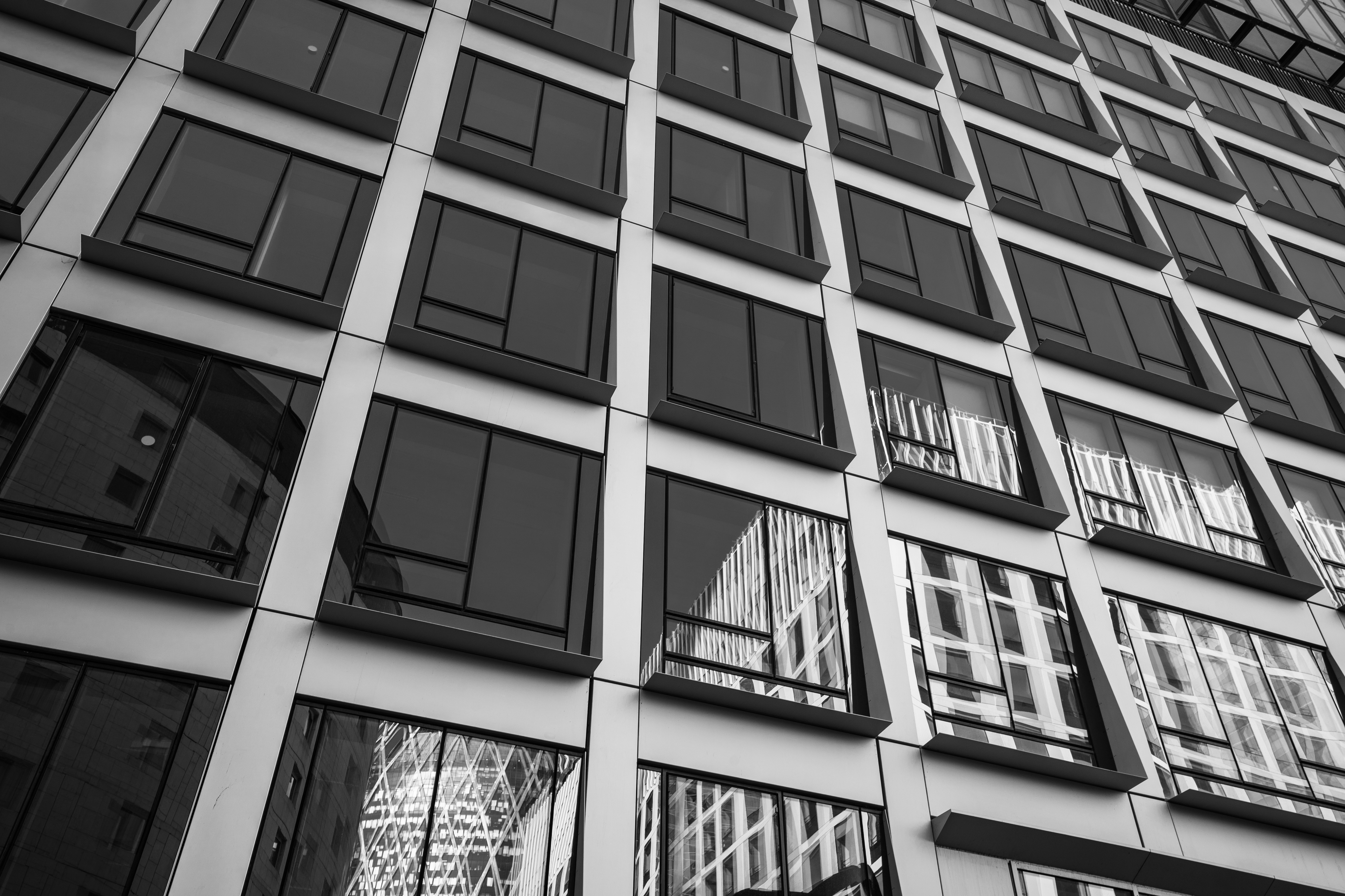 Modern building facade with many windows reflecting skyward