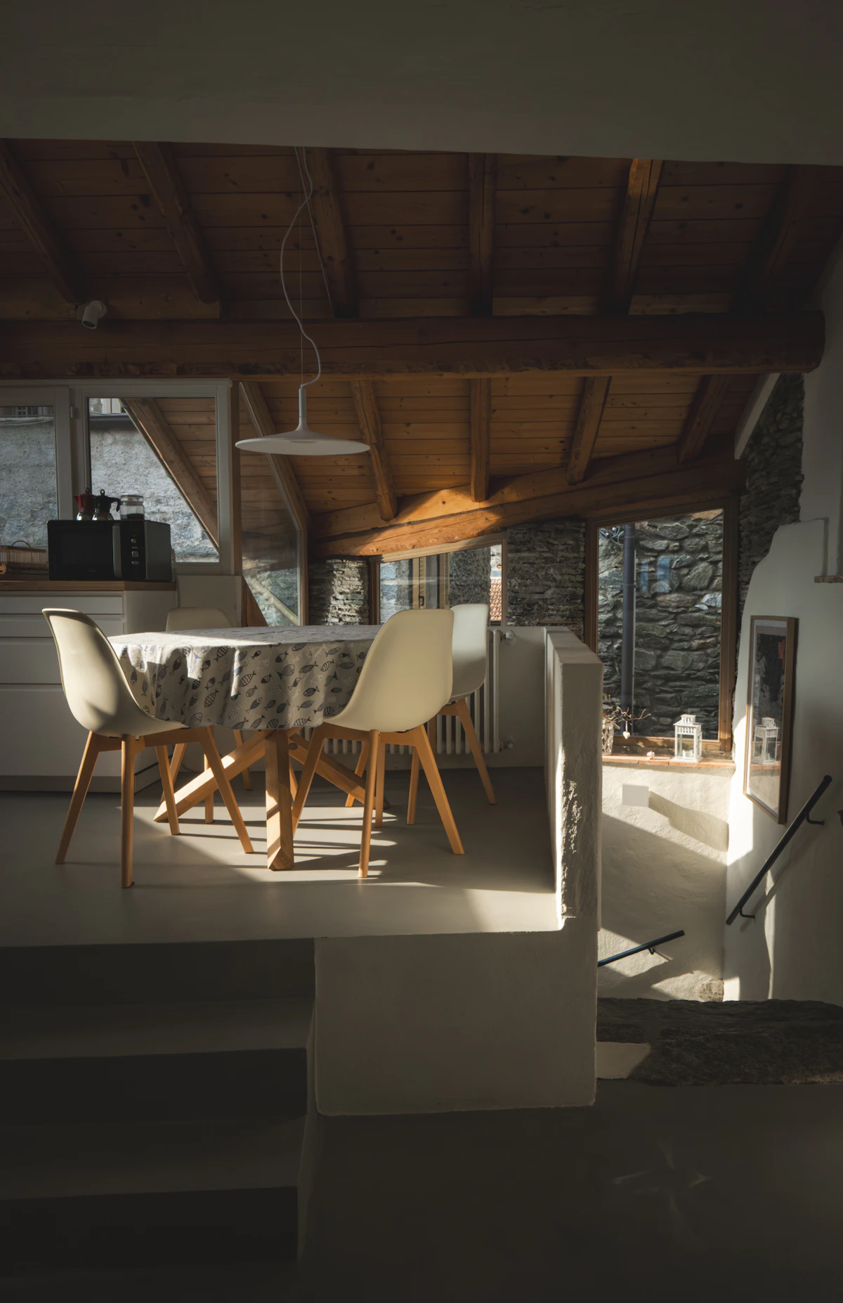 Comedor bajo vigas de madera junto a un muro de piedra