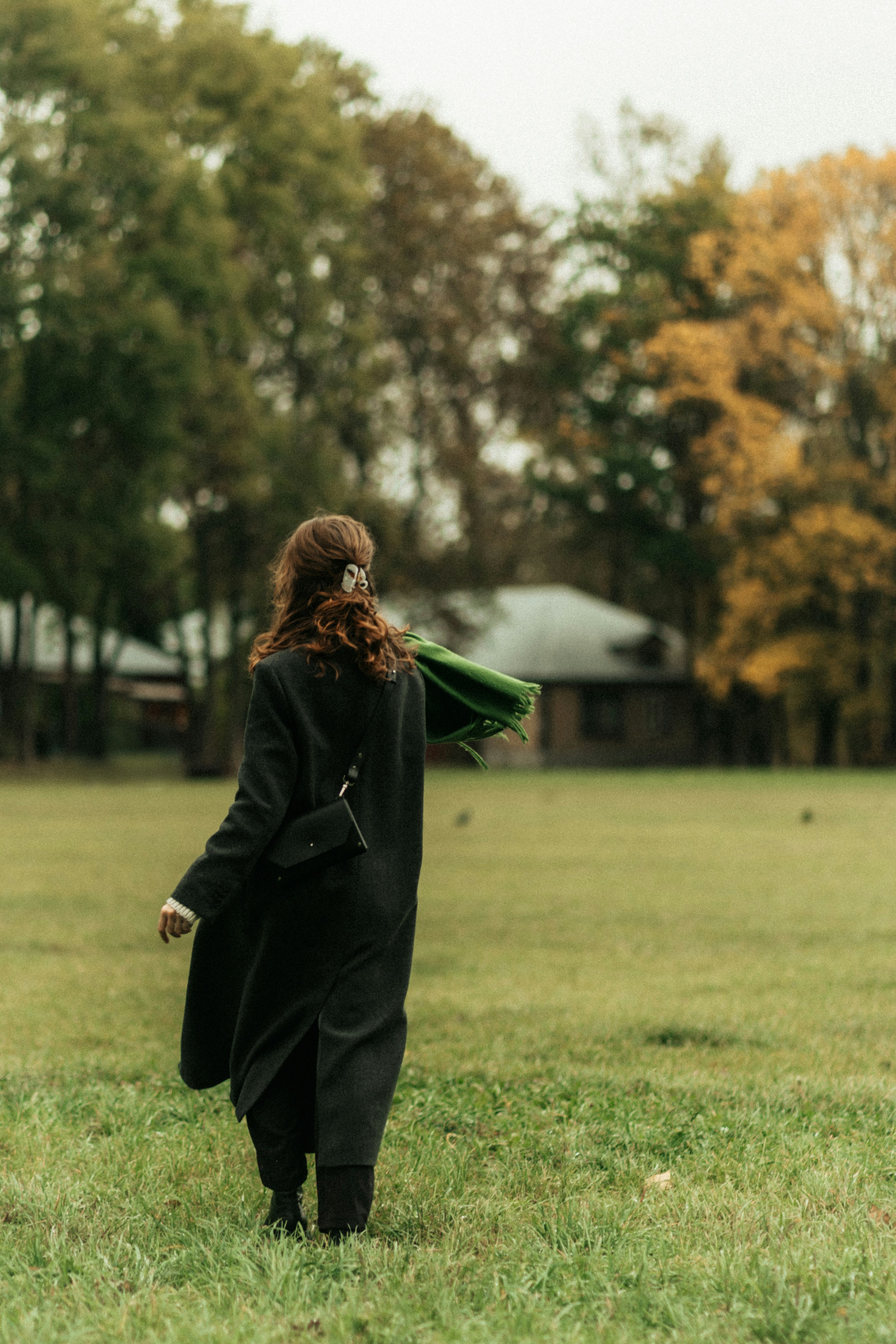 Woman in black coat walking in grassy field