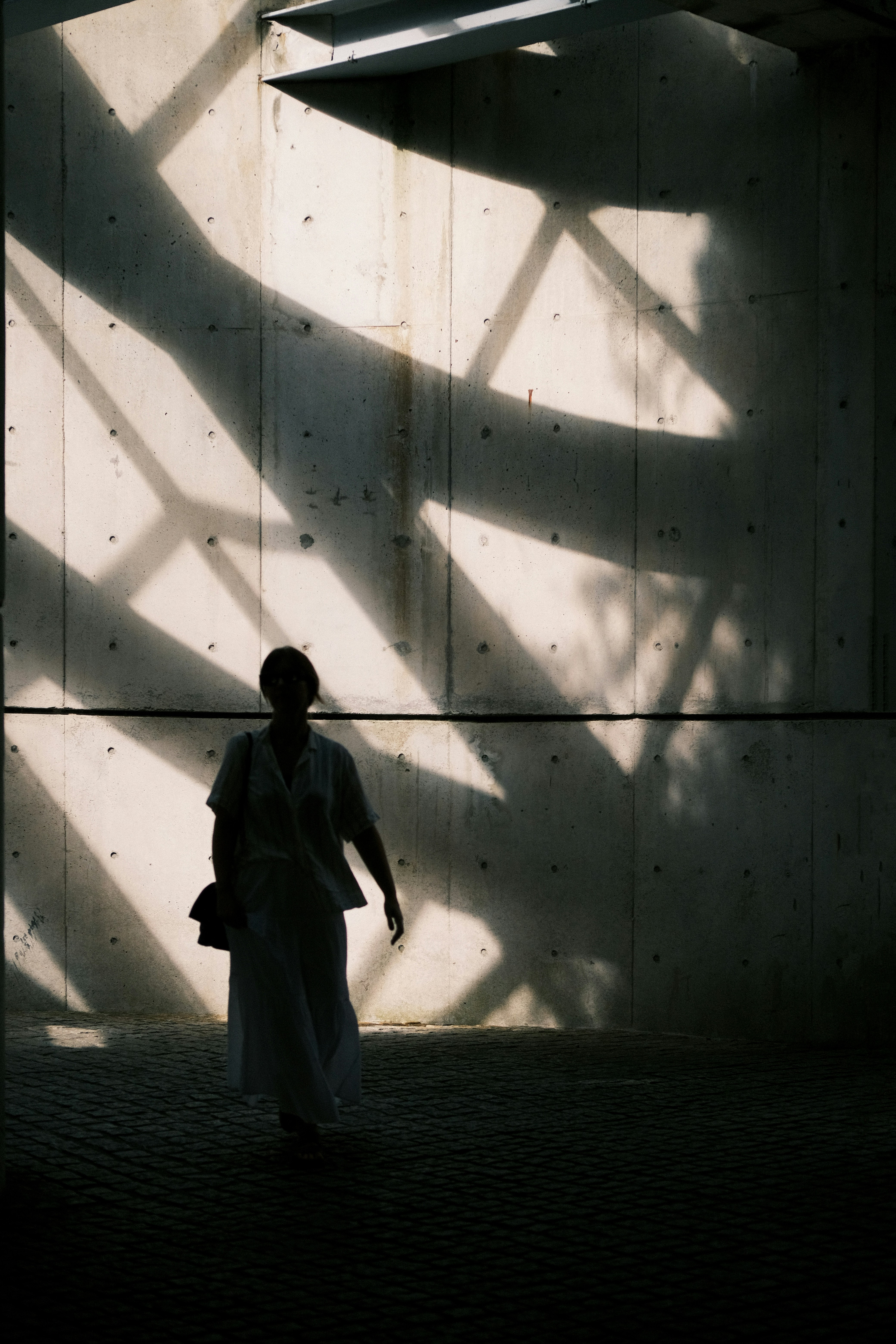 Woman walking in dramatic geometric shadows
