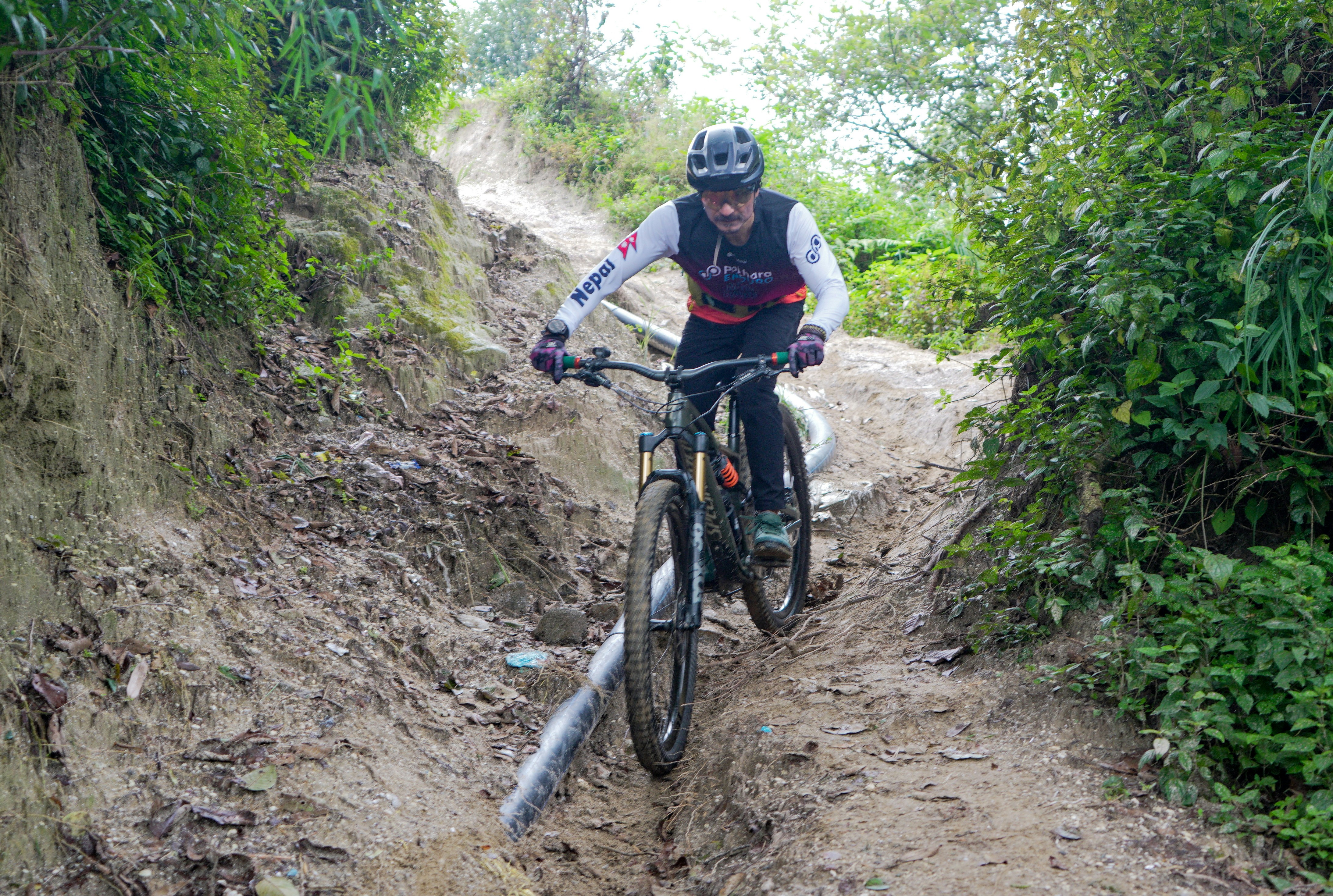 Man rides mountain bike down steep dirt path.