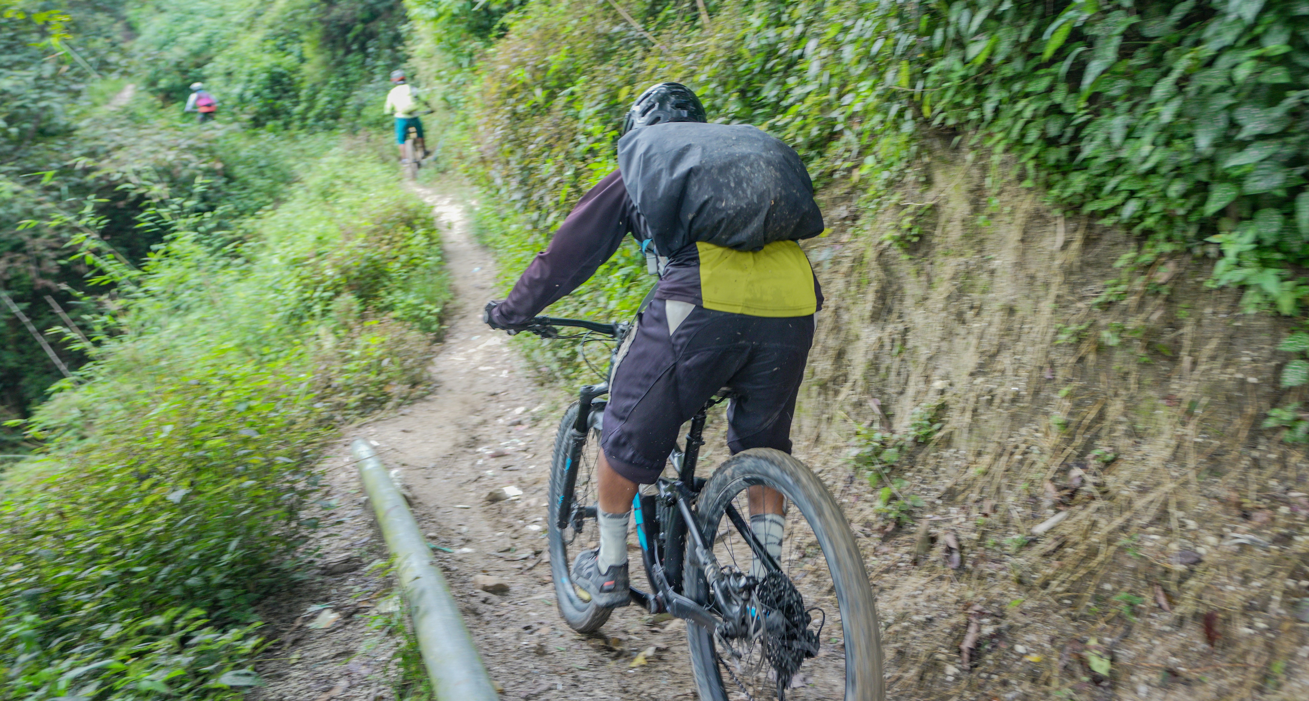 Mountain bikers on a narrow, dirt trail.