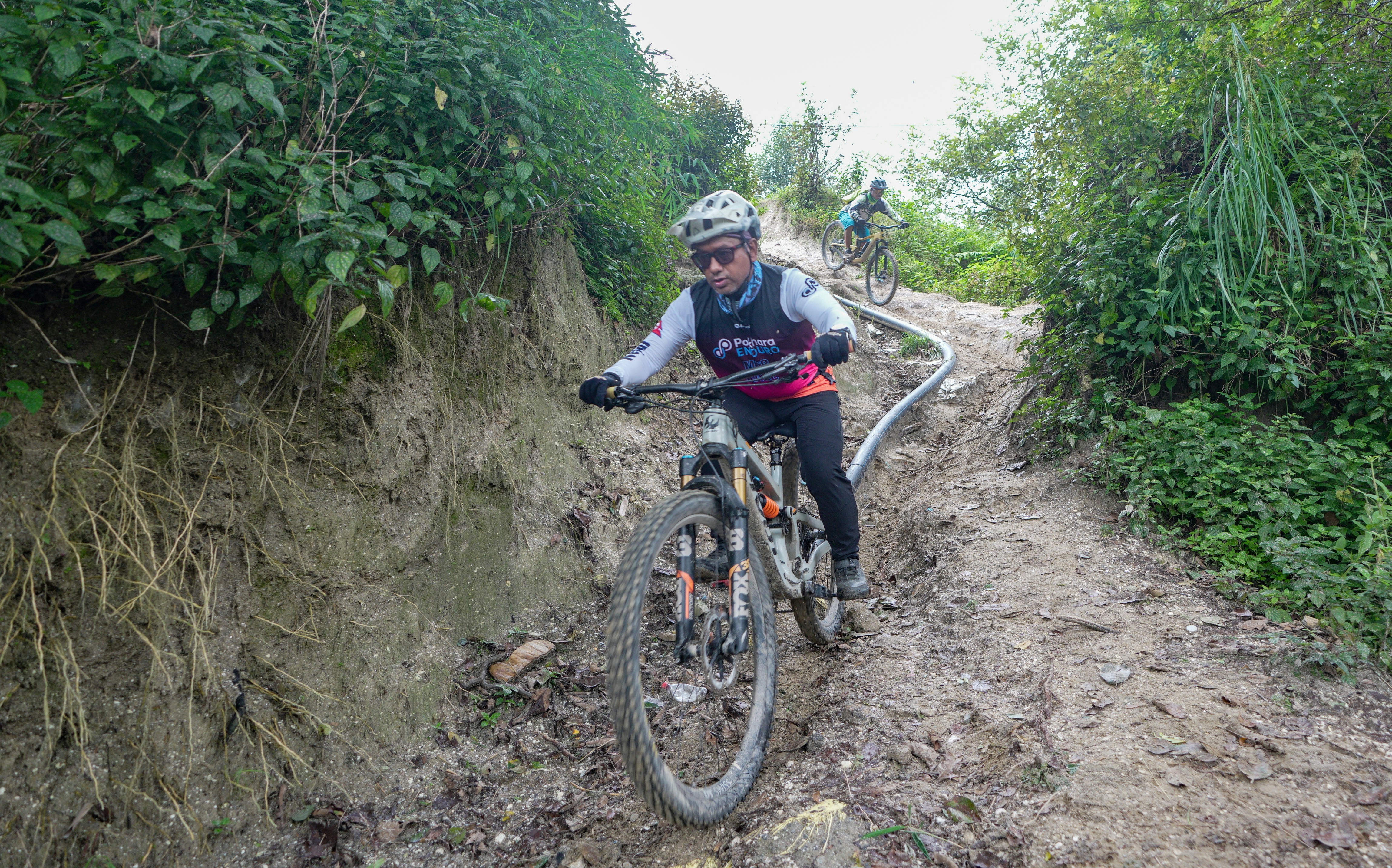 Woman riding a mountain bike on a muddy trail.