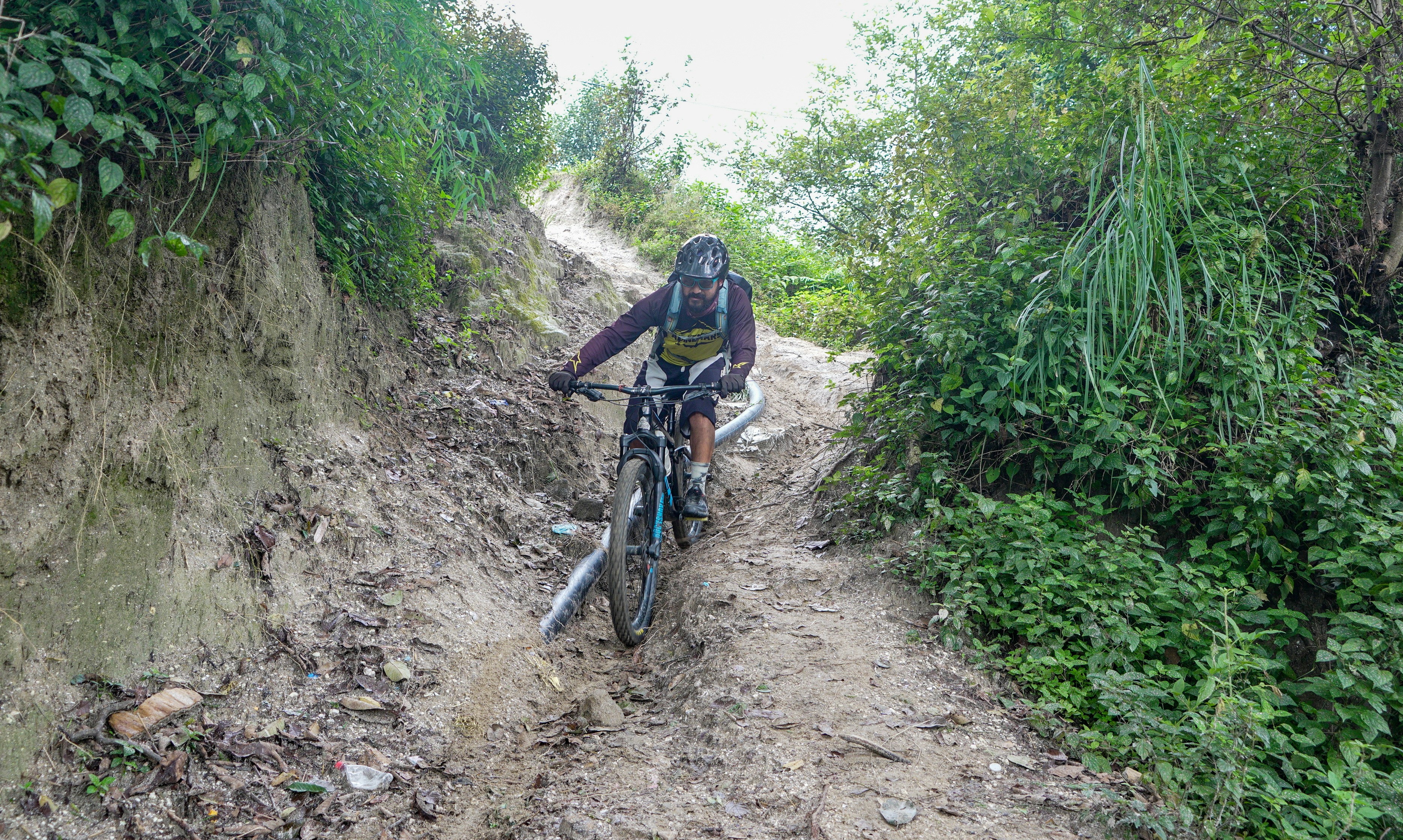 Mountain biker descends a steep, muddy trail.