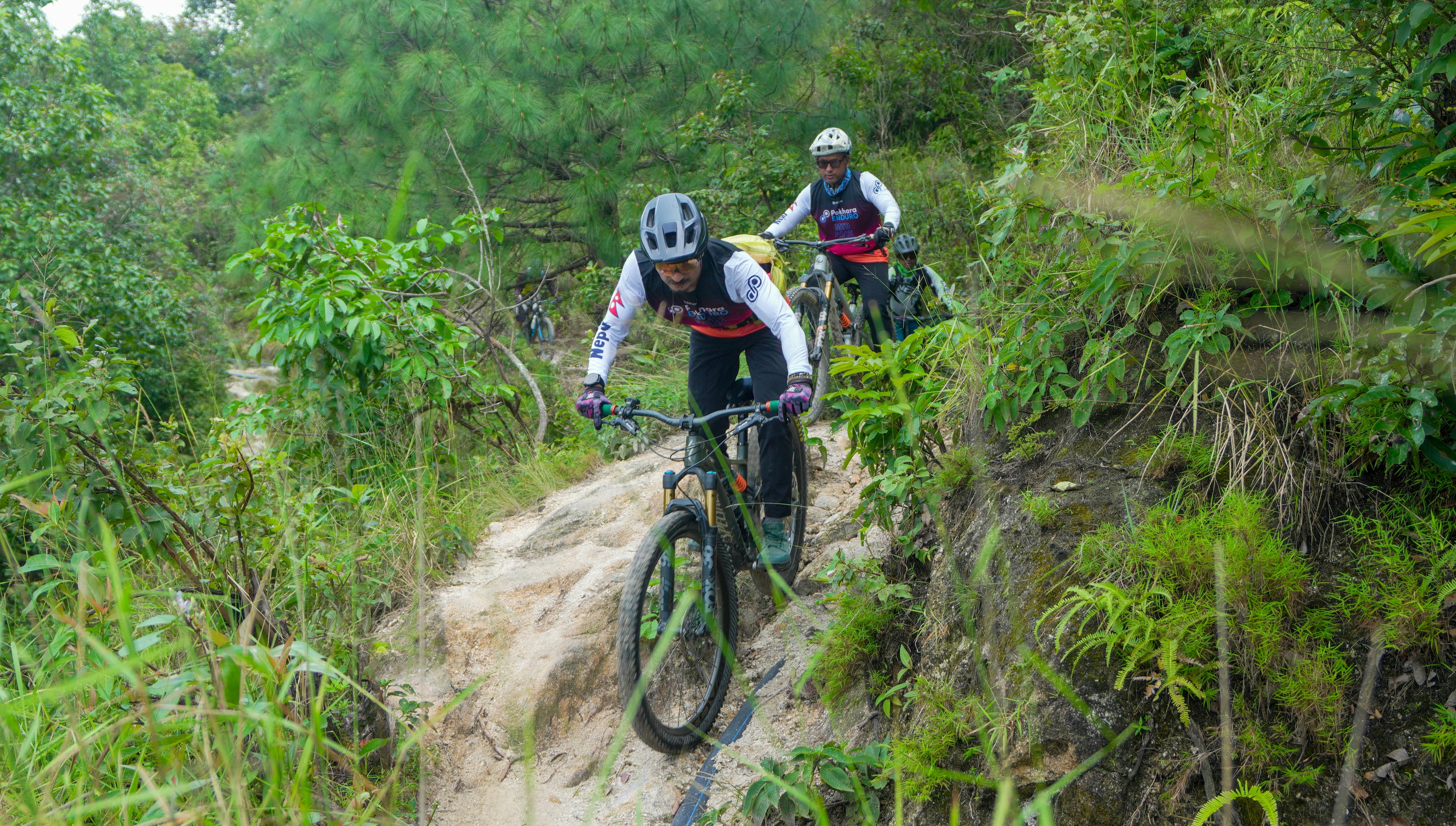 Two cyclists riding mountain bikes on a dirt path.
