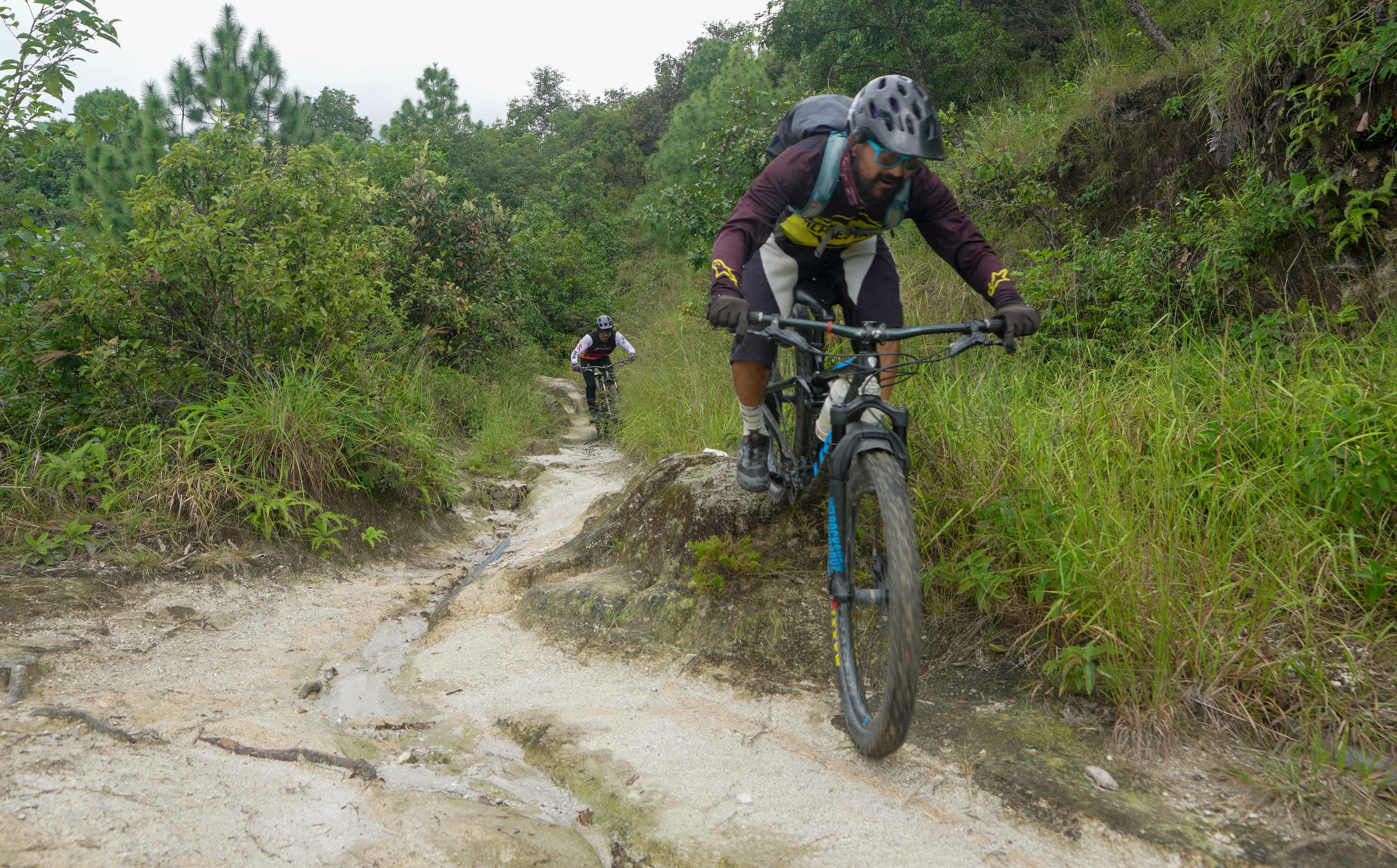 Two cyclists riding down a dirt path.
