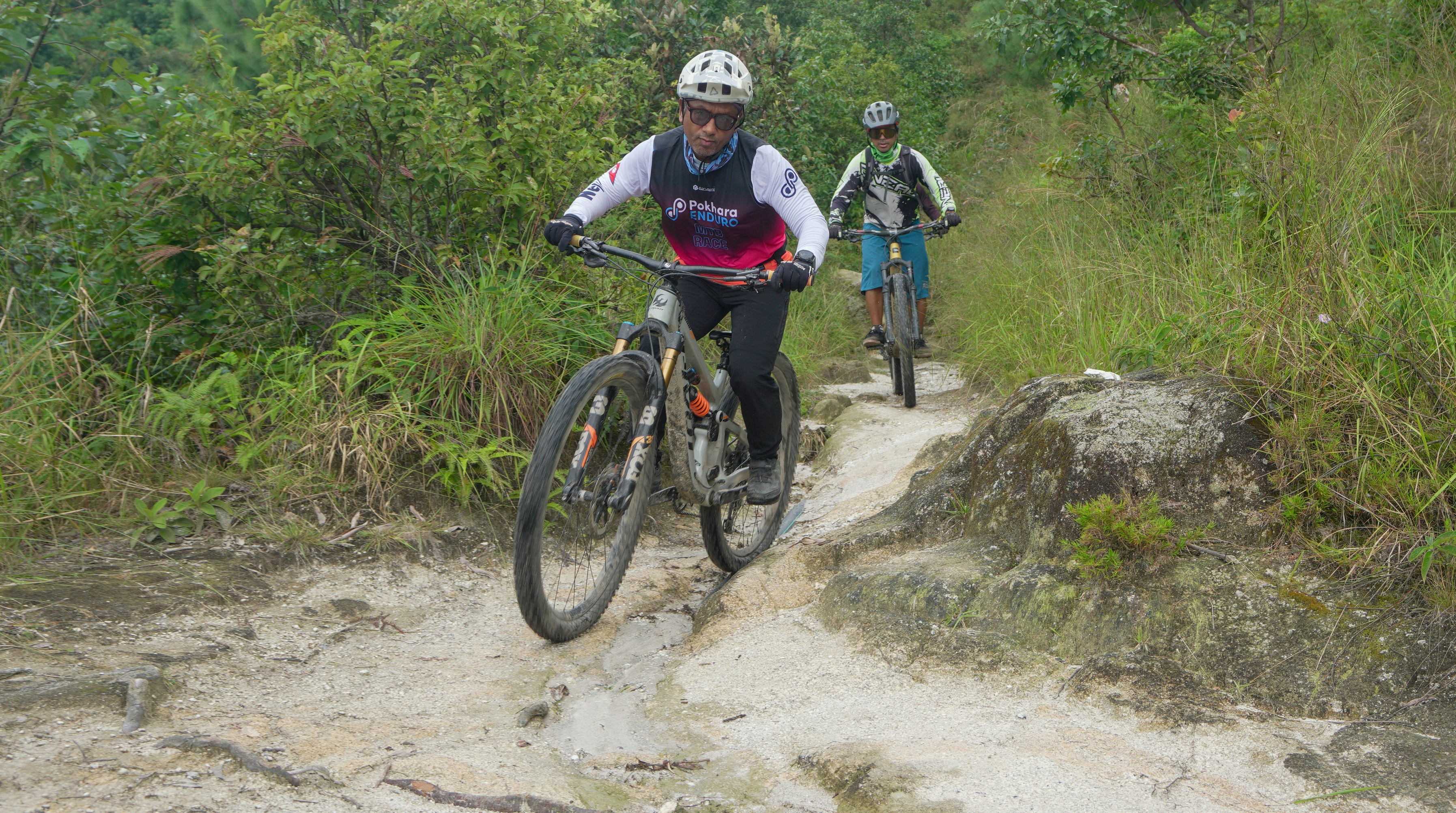 Two cyclists riding on a rocky dirt path.
