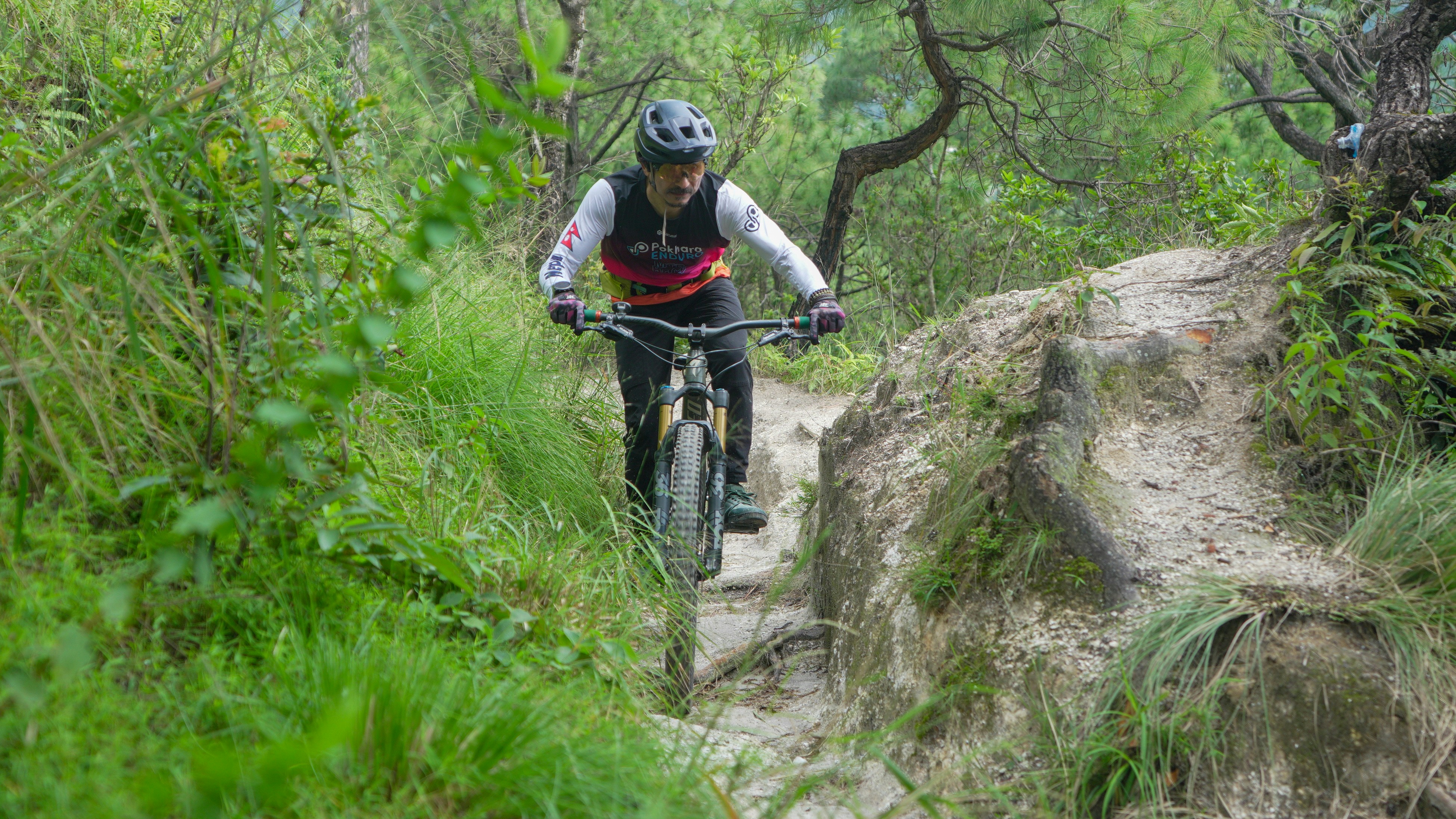 Man riding a mountain bike on a narrow trail.