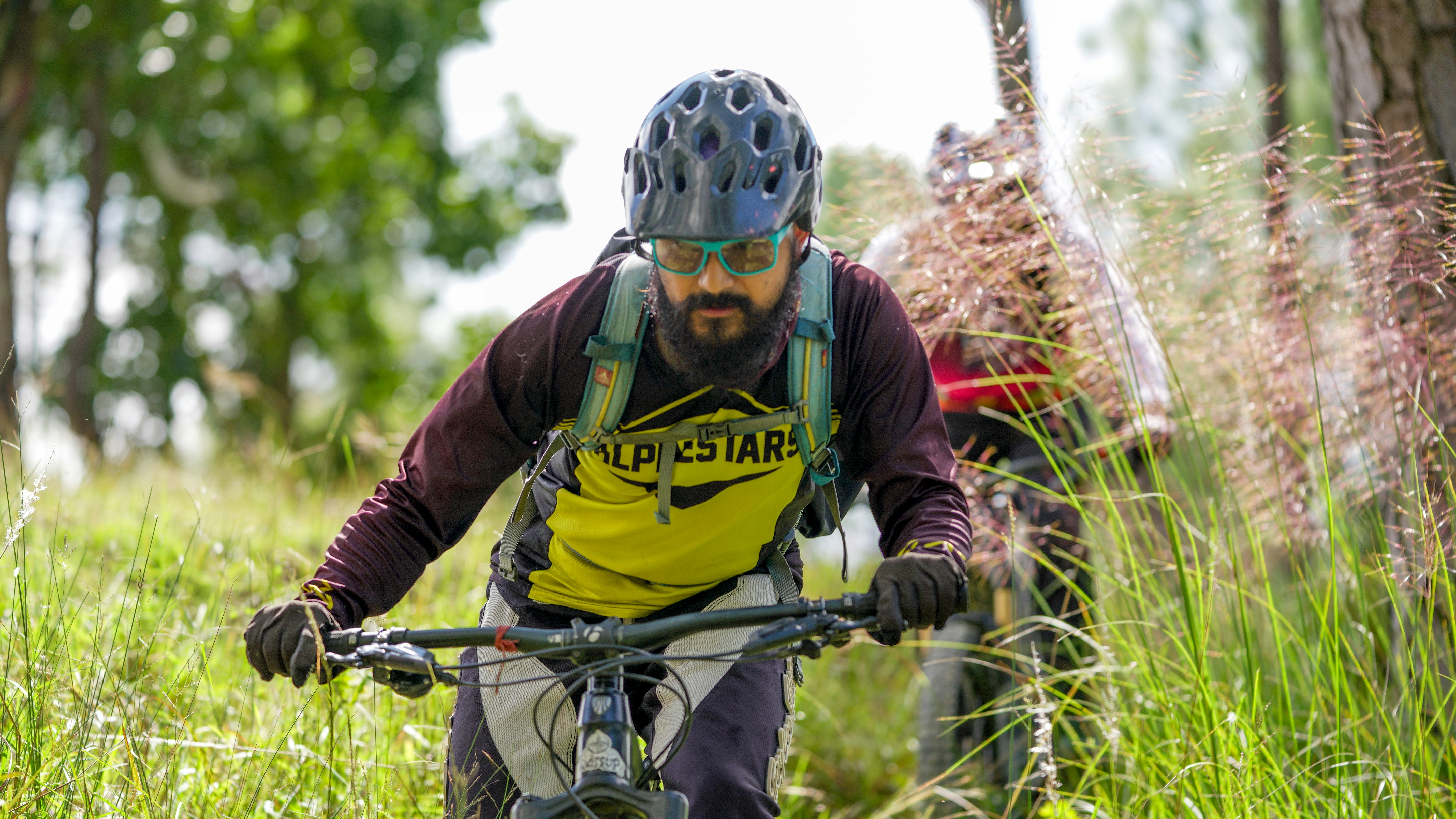 Man riding a mountain bike through grassy trail.
