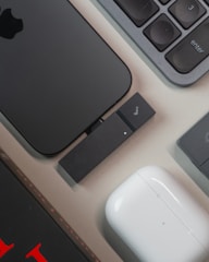 Smartphone, keyboard, and wireless earbuds on a desk.