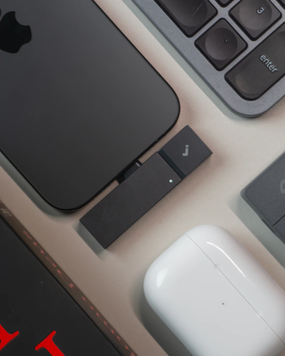 Keyboard, smartphone, and wireless earbuds arranged on a modern desk