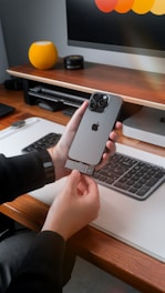Person attaching accessory to iPhone near keyboard